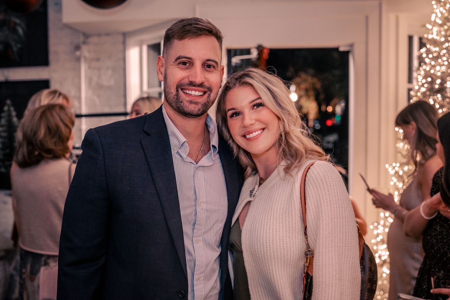 Partygoers smiling and posing together at a festive indoor celebration with string lights.