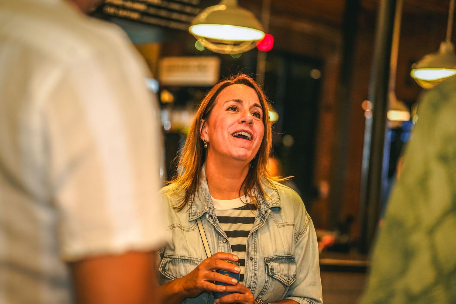 People enjoying conversation and drinks at a social gathering with ambient lighting.