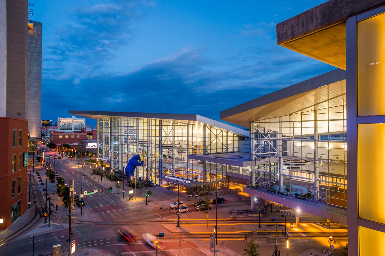 Modern convention center illuminated at dusk with glass walls and city street in downtown Louisville, Kentucky.