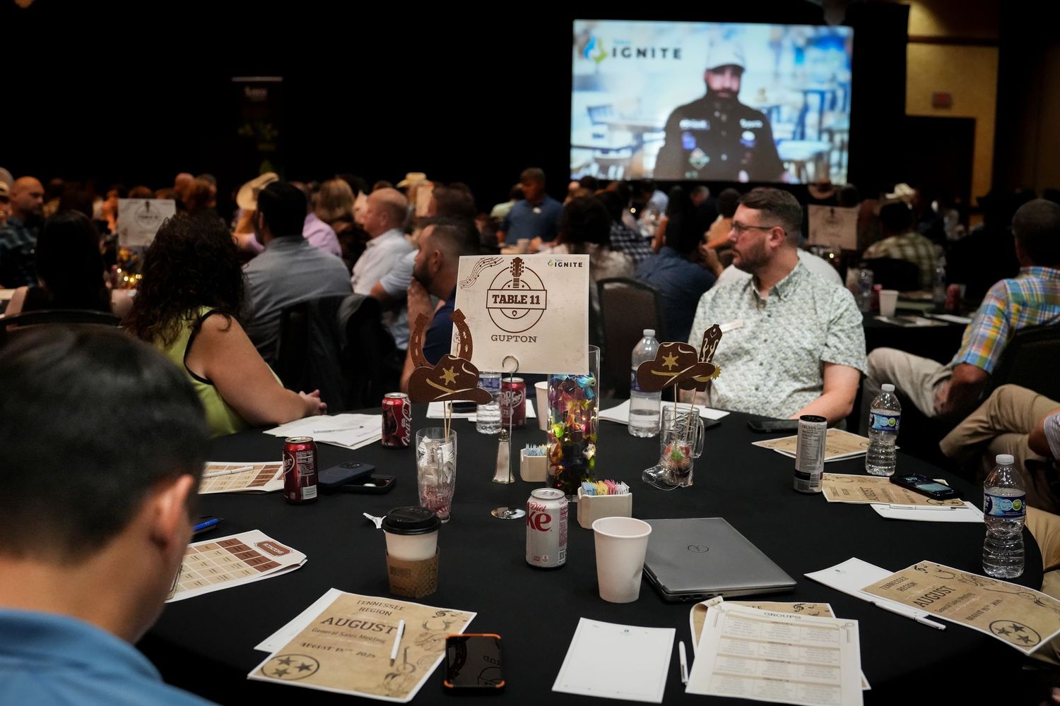 Conference attendees seated at tables during a business presentation.
