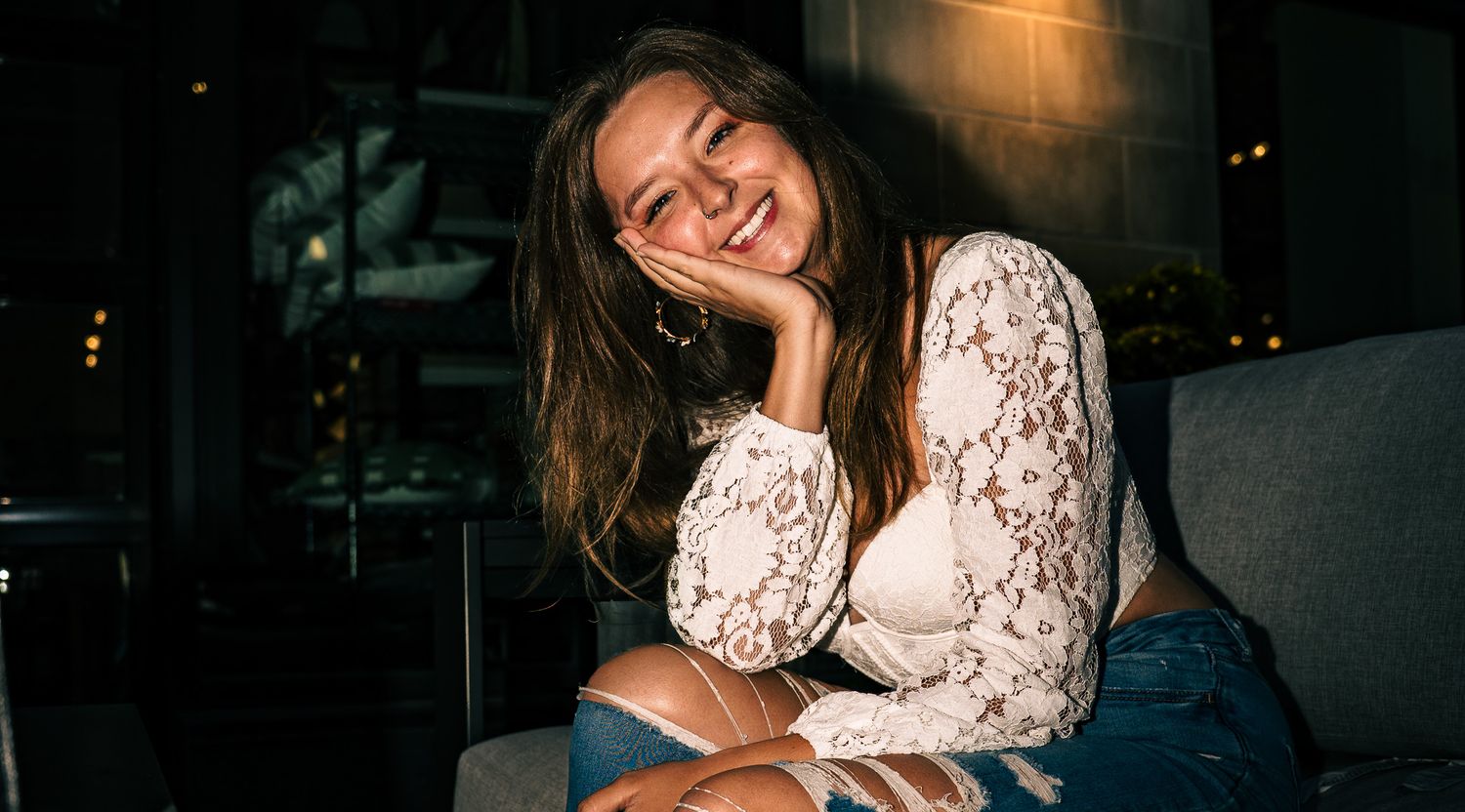 Professional portrait photo of a person standing outdoors with soft natural lighting.