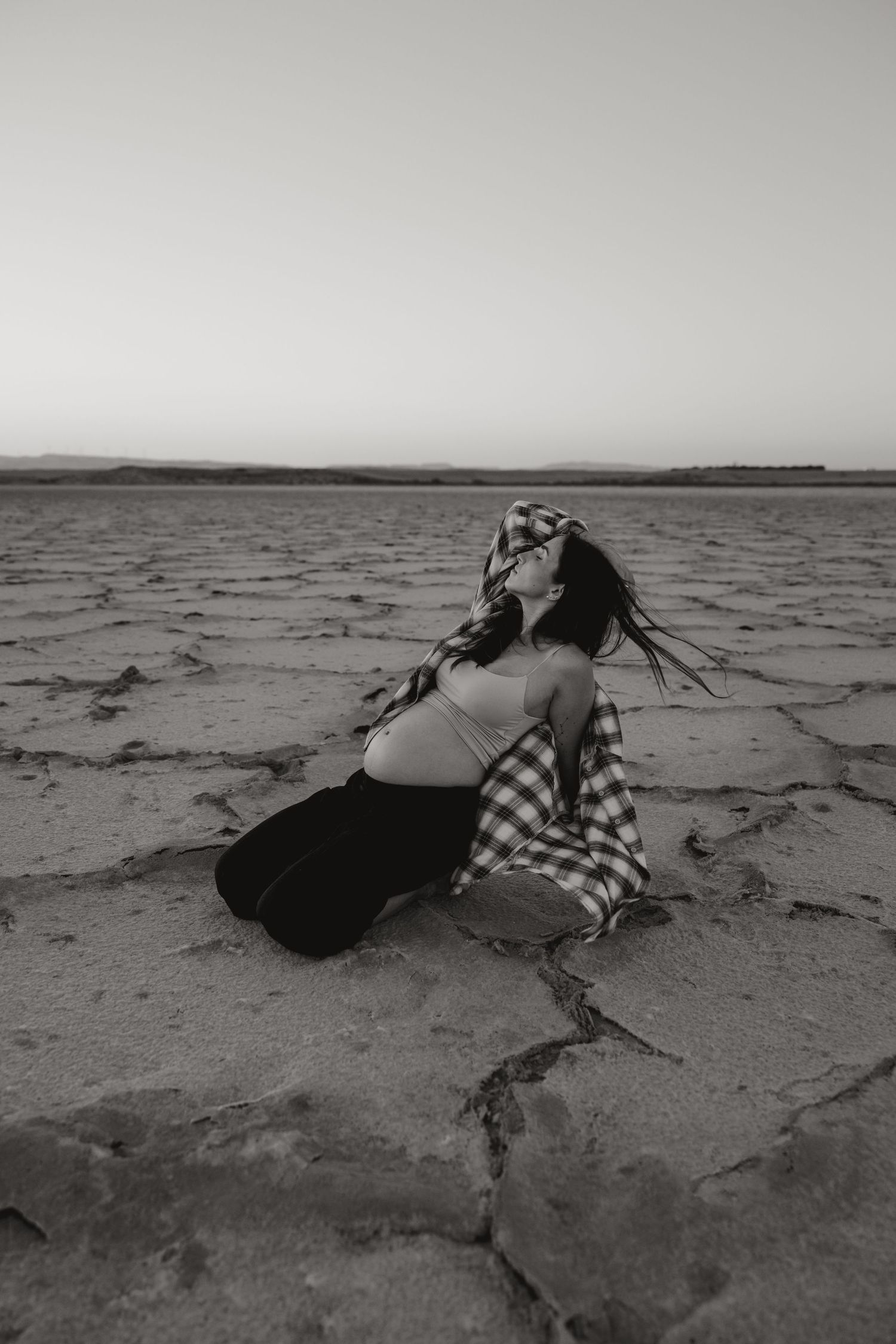 Woman lying on cracked earth during an artistic outdoor photoshoot in Cyprus
