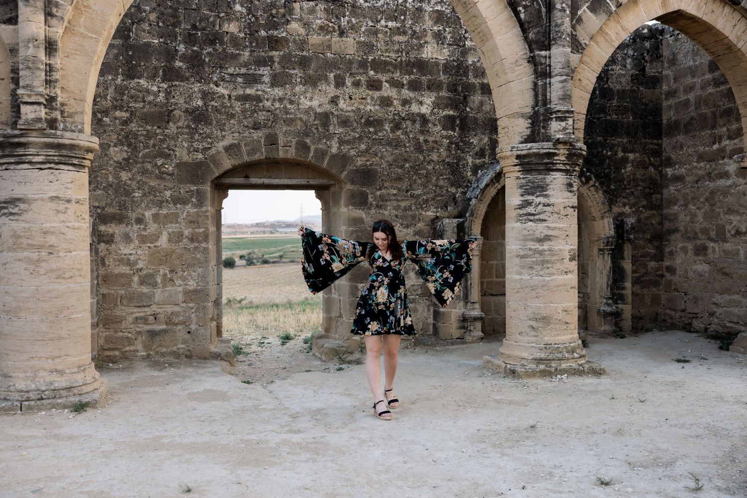 Woman standing under historic stone arches during a portrait photoshoot in Cyprus
