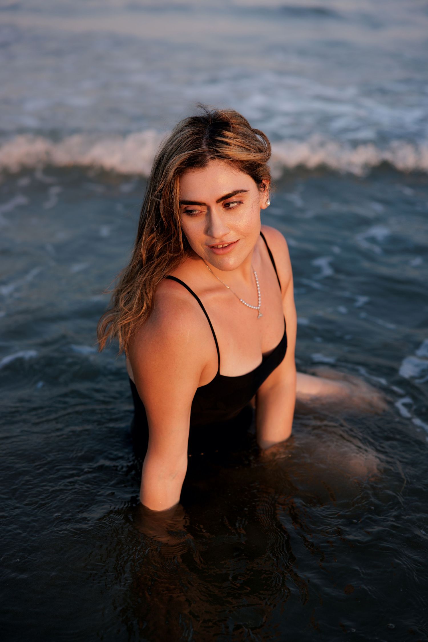 Woman standing in shallow water during a sunset beach photoshoot in Cyprus