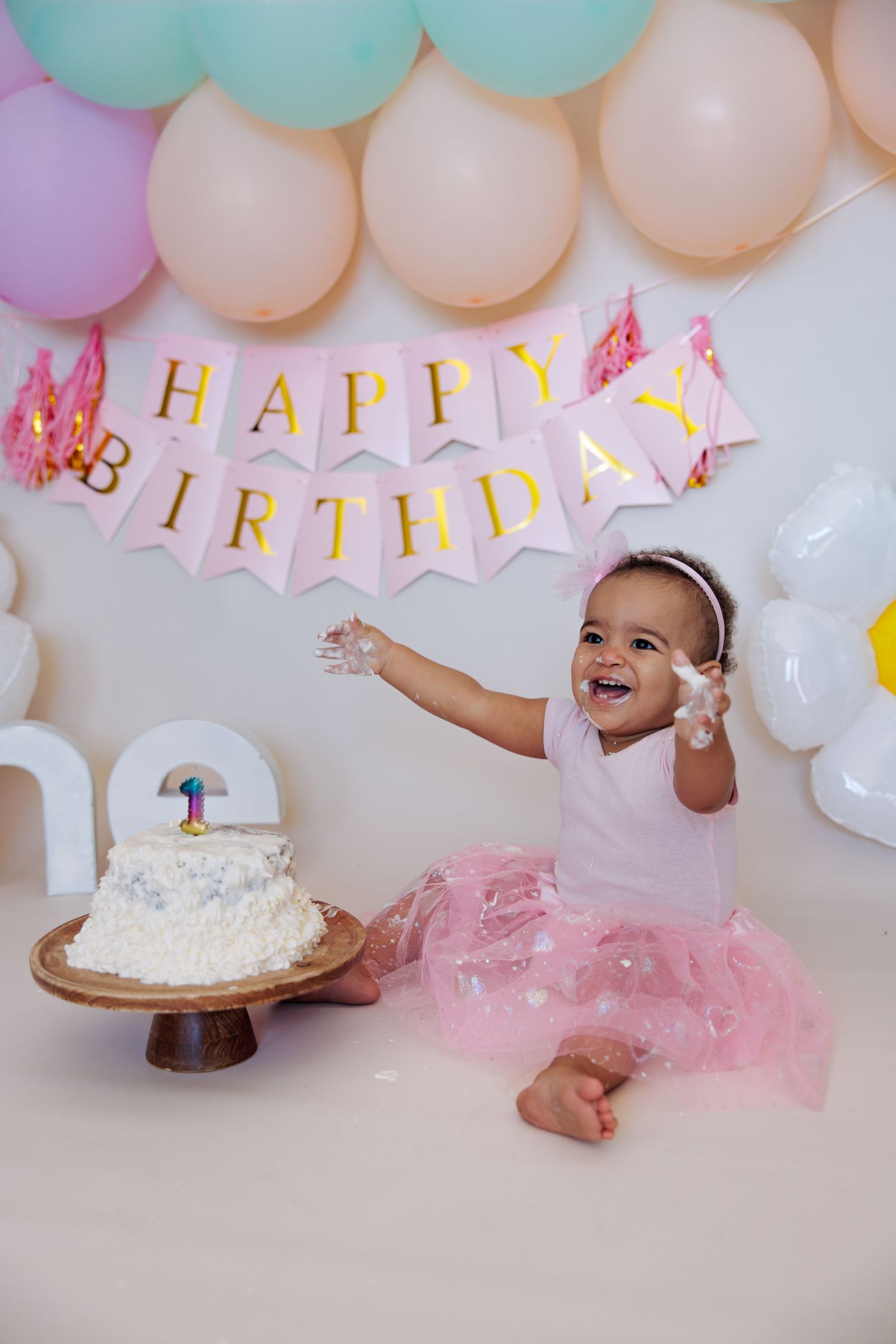 Baby girl sitting in front of birthday balloons during a first-birthday photoshoot in Cyprus