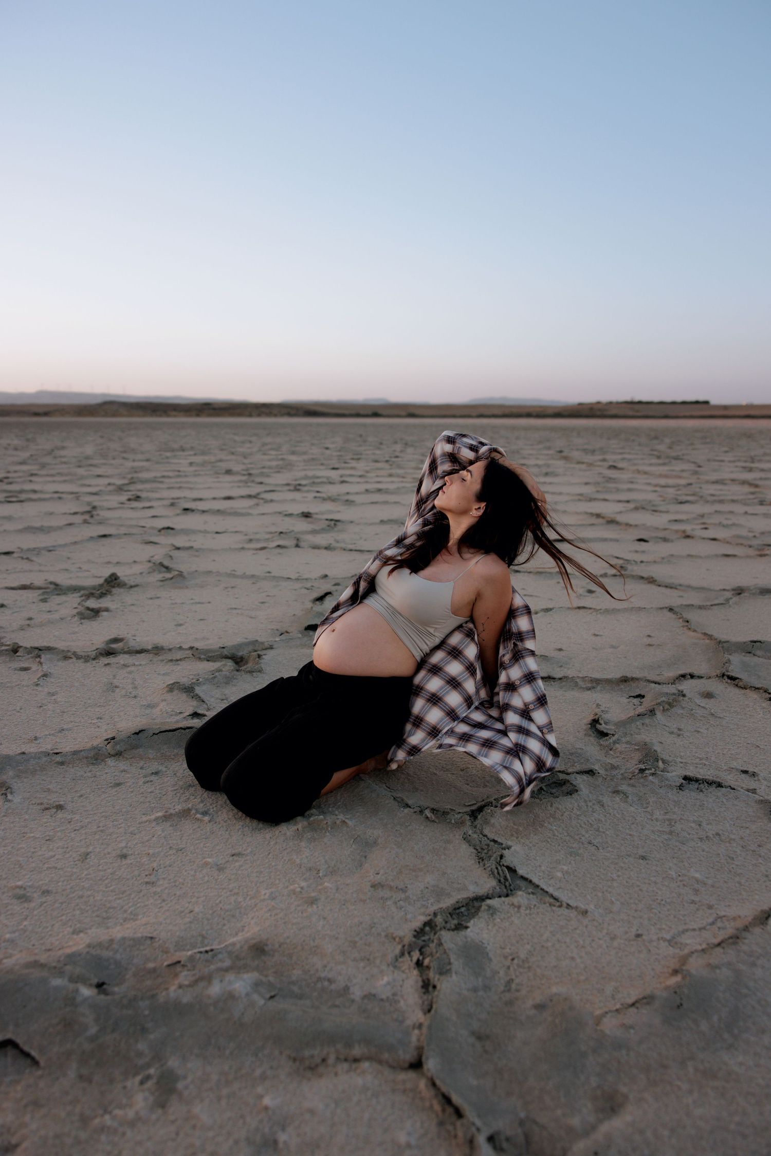 Pregnant Woman lying on the sand during a sunset beach photoshoot in Cyprus