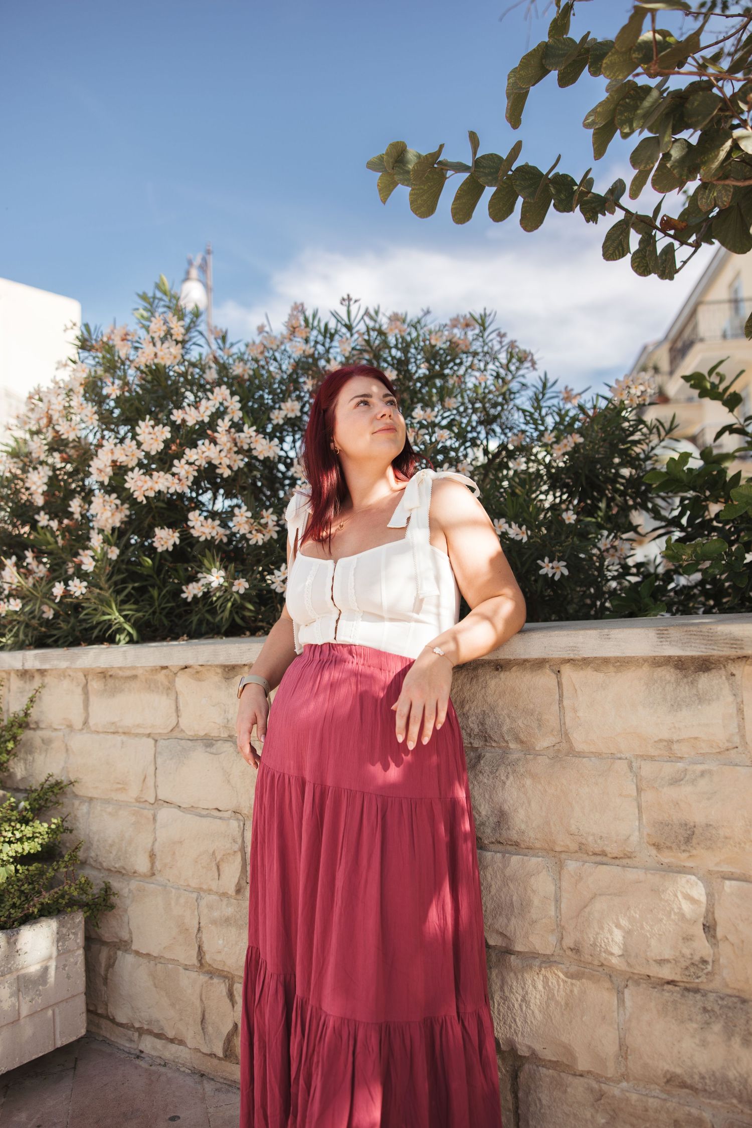 Woman in a red dress standing near flowers during a summer photoshoot in Cyprus