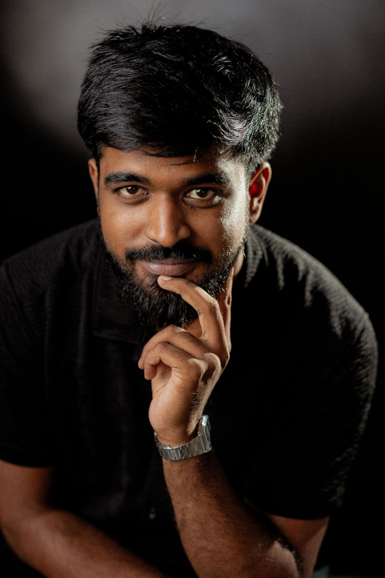 A dramatic series of portrait shots showing a figure in black against a dark background with contemplative expressions.