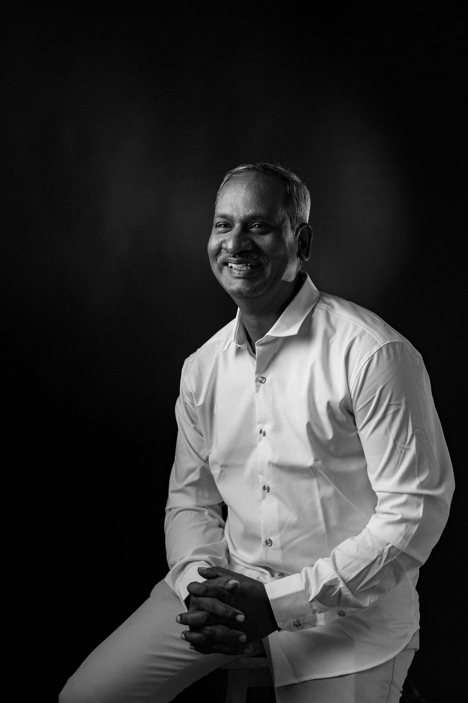 Professional black and white studio portrait in three artistic poses showing a person in a white dress shirt.