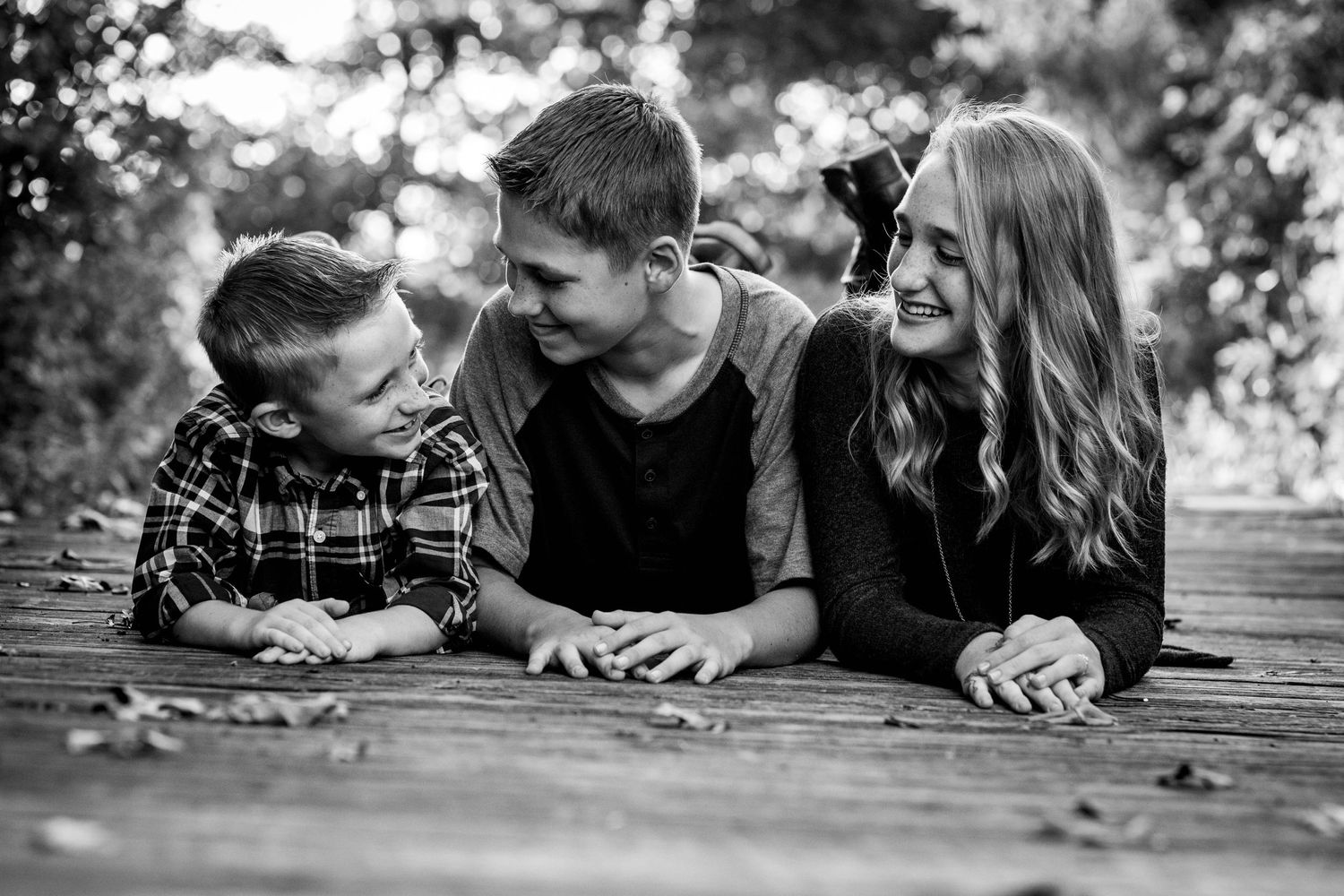 Family lying together on wooden deck during casual photo session.