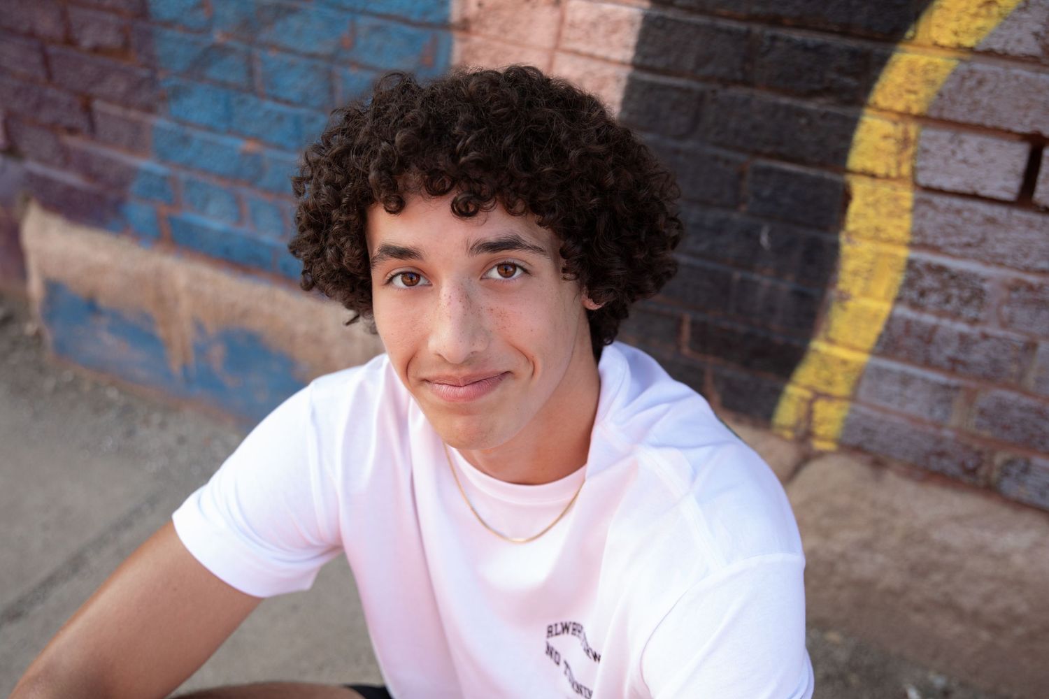 Portrait series against a brick wall with yellow stripe showing different casual poses.