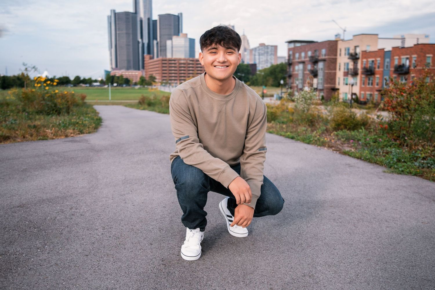 Urban portrait with Detroit skyline featuring casual attire and modern architecture.