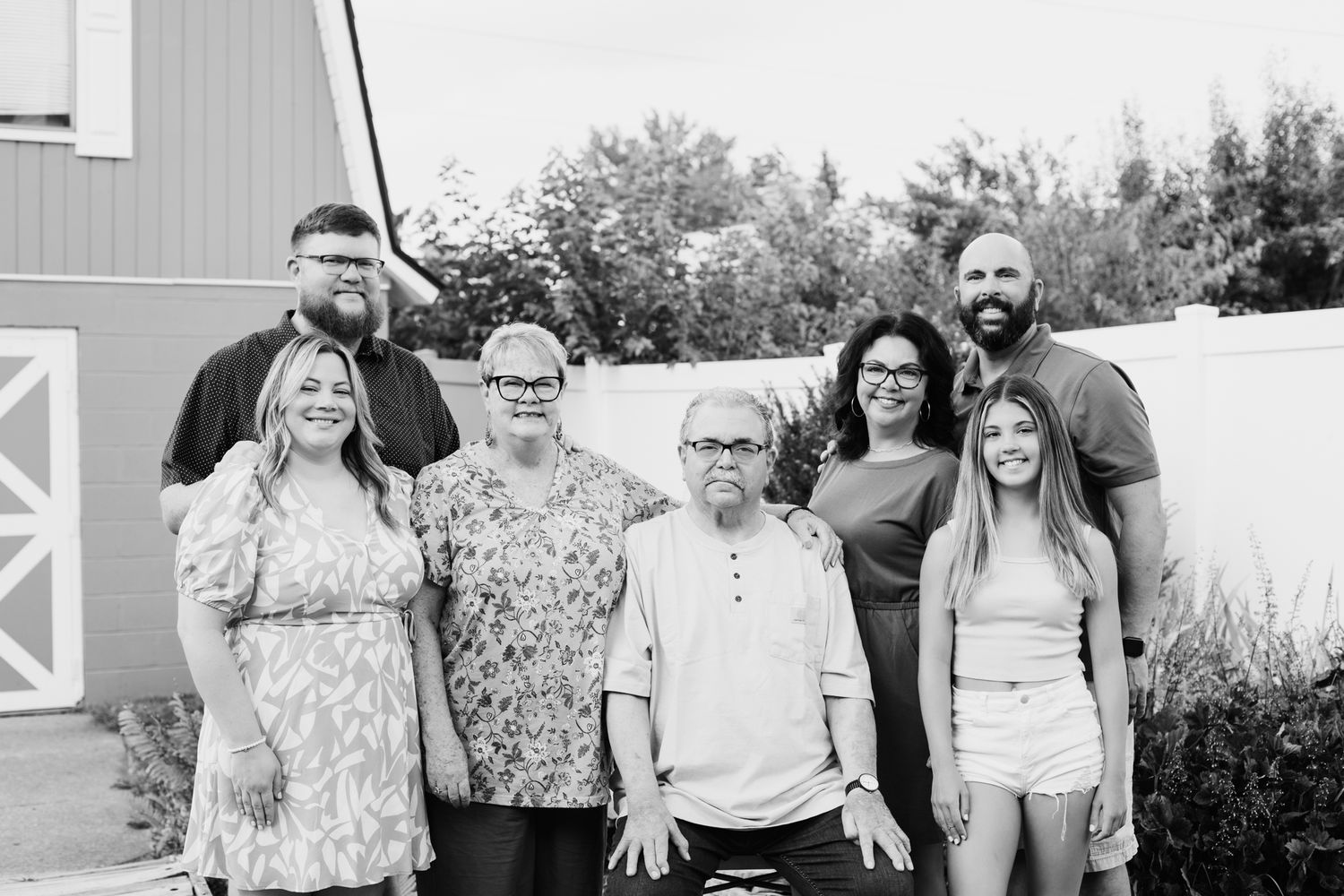 Group portrait outdoors against a rustic barn setting in casual attire.