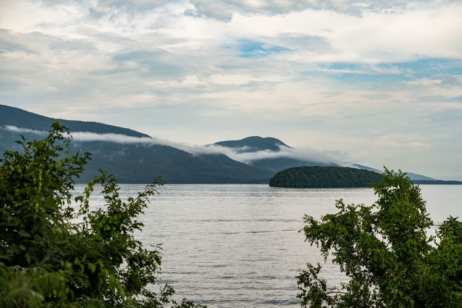 Scenic panoramic view of a misty coastline with mountains, islands, and evergreen trees along the Pacific Northwest shore.