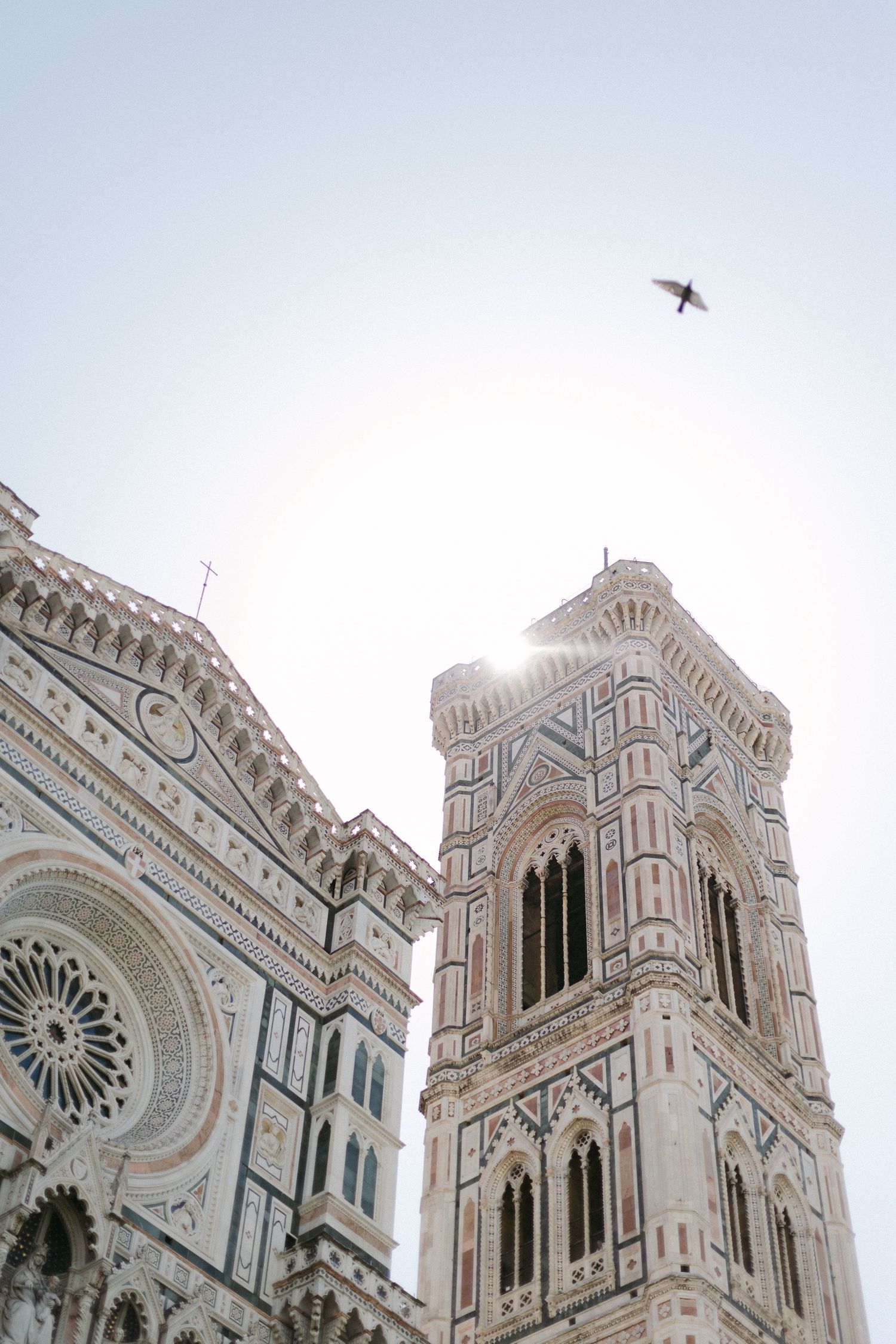 The historic Florence Cathedral's ornate Gothic architecture and iconic dome rises against a bright blue sky in Italy.