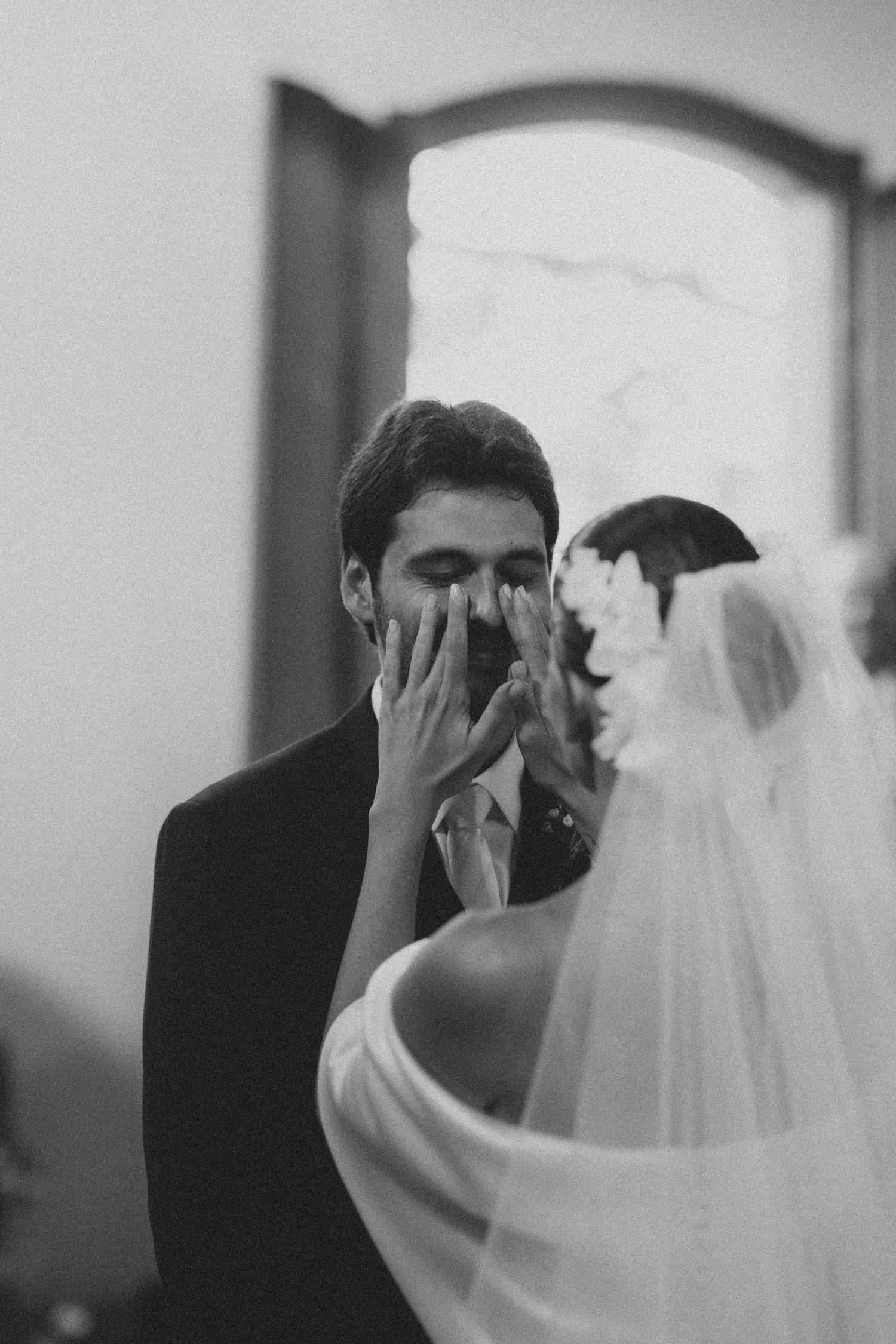 A black and white sequence showing a gentle first look between a couple on their wedding day, with a flowing veil.