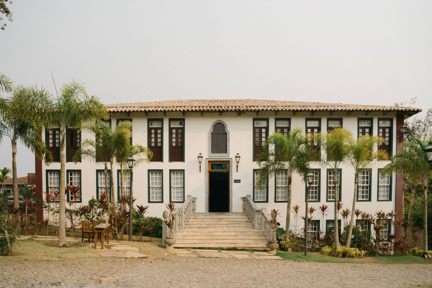 A series of colonial-style buildings with white walls and terracotta roofs line up along a historic street in Brazil.