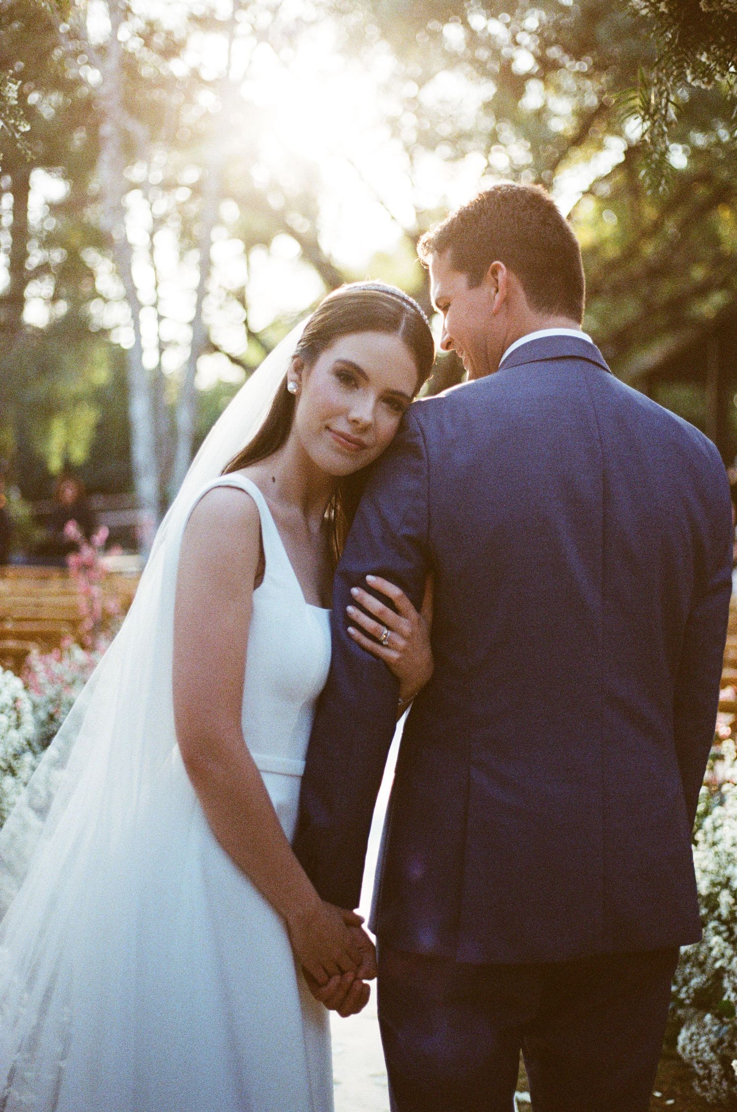A series of intimate wedding photos showing tender moments between a bride in white and groom in navy during golden hour.
