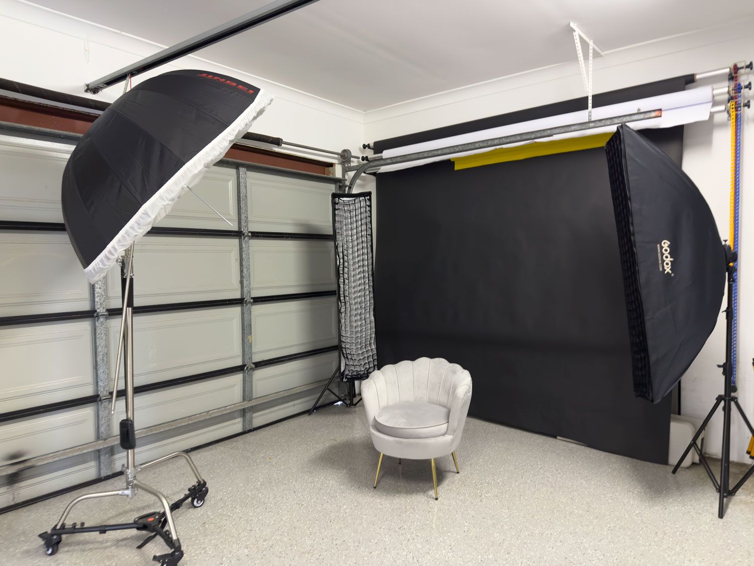 Wollongong professional photography studio with softbox lights, umbrella flash, and a white velvet chair on a dark backdrop.