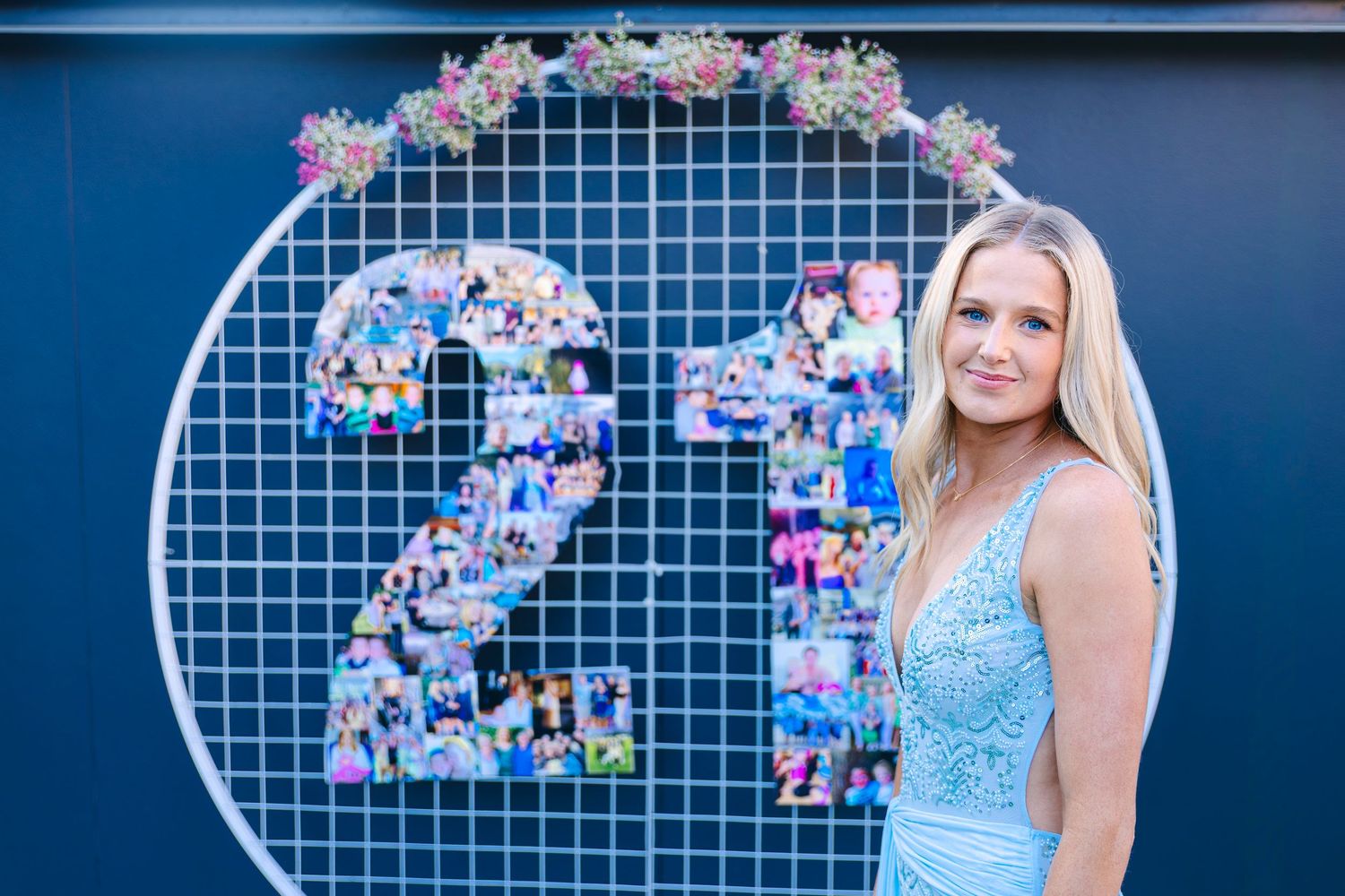 Young blonde woman poses beside a photo collage number 21 display with floral arch for birthday. Wollongong Event Photography
