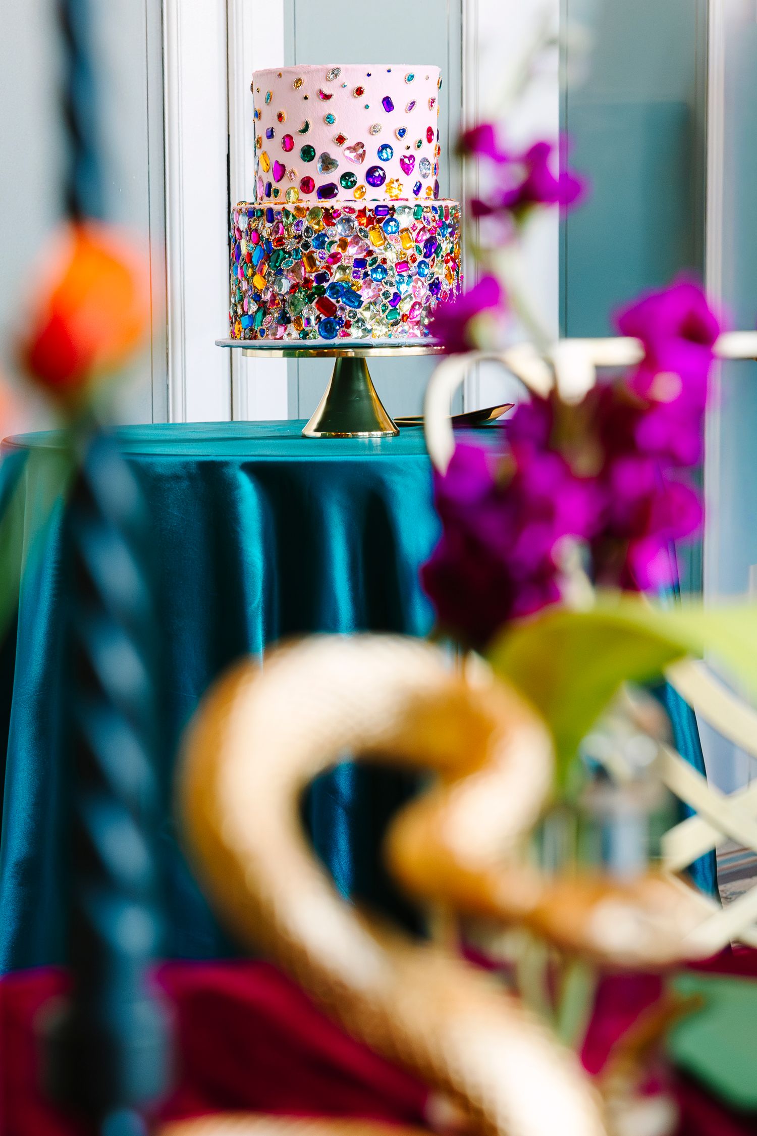 Wollongong Wedding Photographer. A two-tier white wedding cake with colorful confetti dots displayed on a gold stand.