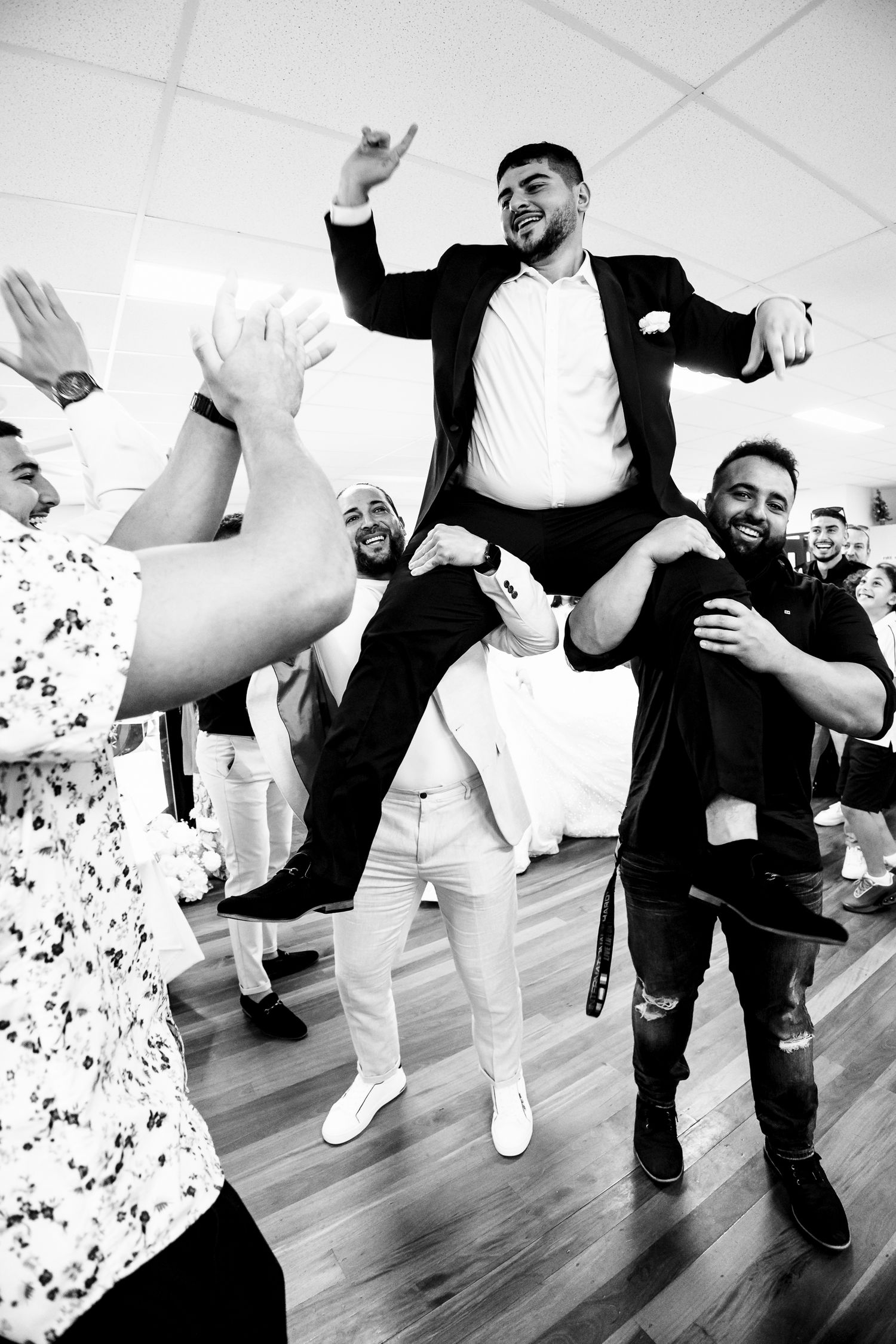 Groom lifted by groomsmen during joyful wedding reception dance celebration in black and white photo. Wollongong Wedding Photographer