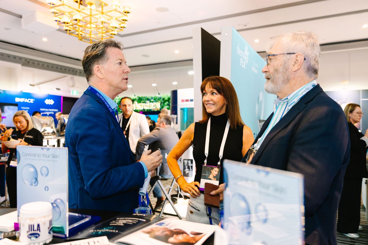 Wollongong Corporate Event Photographer. Professionals networking at a trade show booth, engaged in conversation at an conference event.