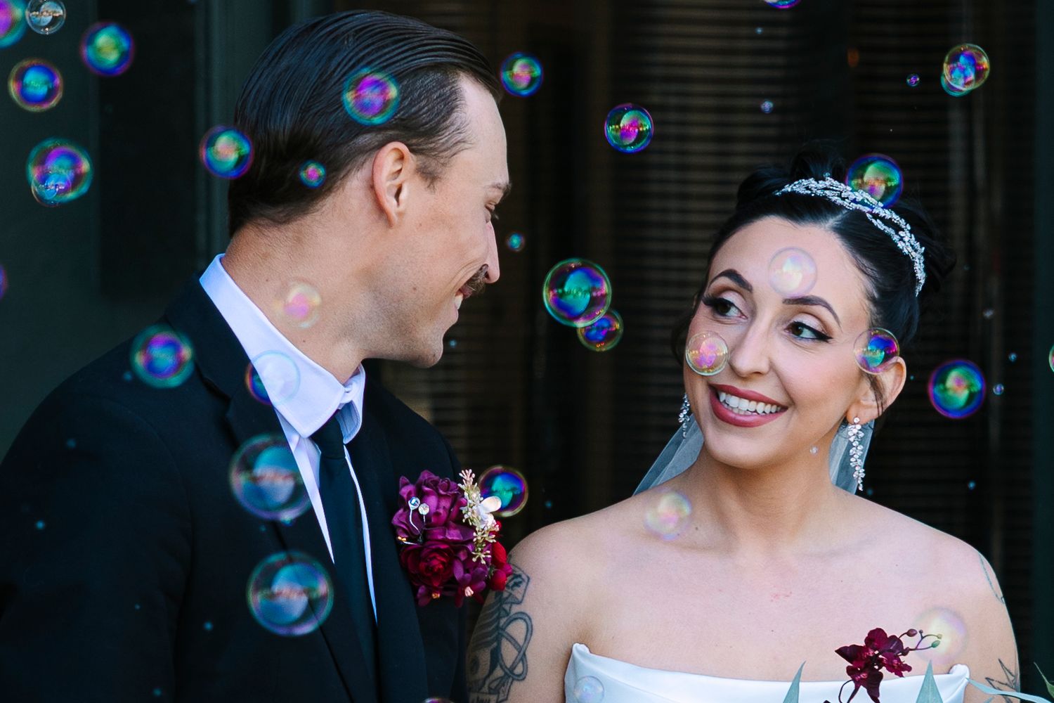 Bride and groom smiling at each other surrounded by colorful bubbles on their wedding day. Wollongong Wedding Photographer