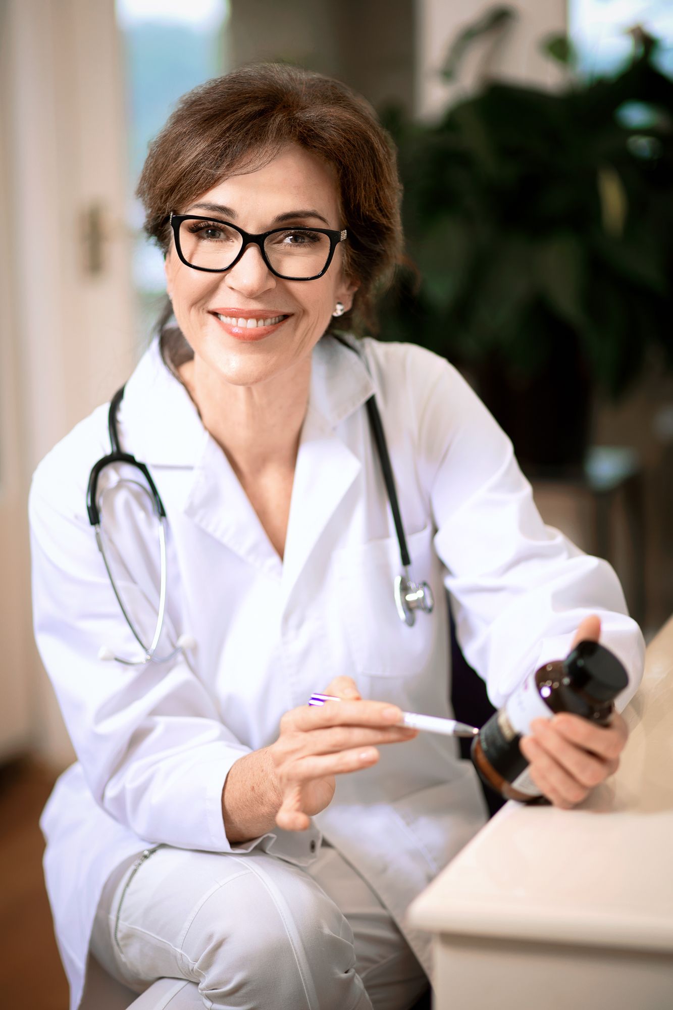 Smiling female doctor in white coat and glasses holding a syringe and medicine bottle. Wollongong Corporate Branding Photographer