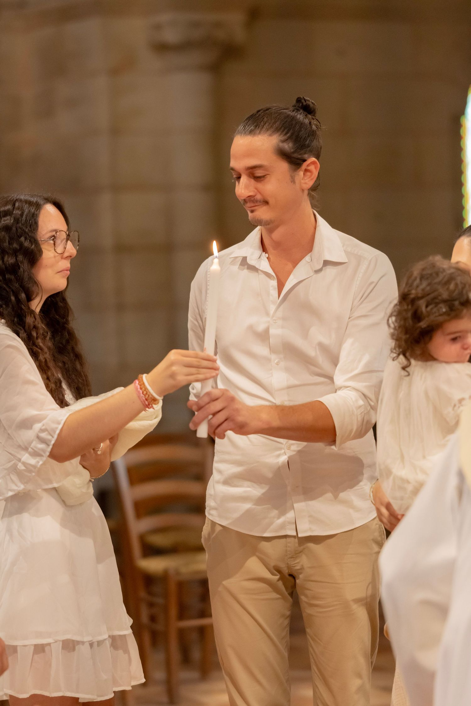 People in white clothing interacting during a celebration or ceremony in a stone-walled venue.