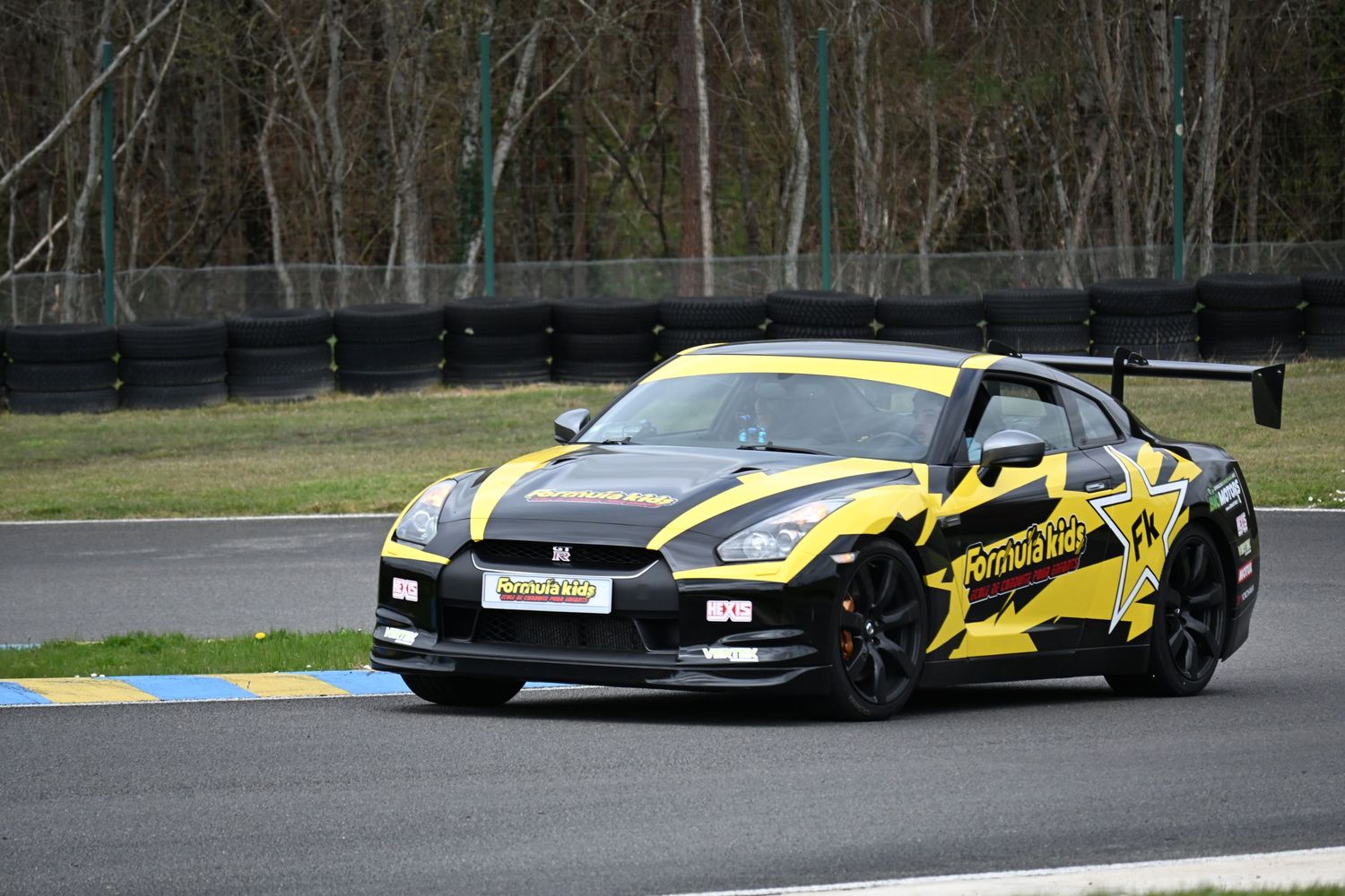 A black and yellow custom Nissan GT-R race car with performance modifications on a racetrack.