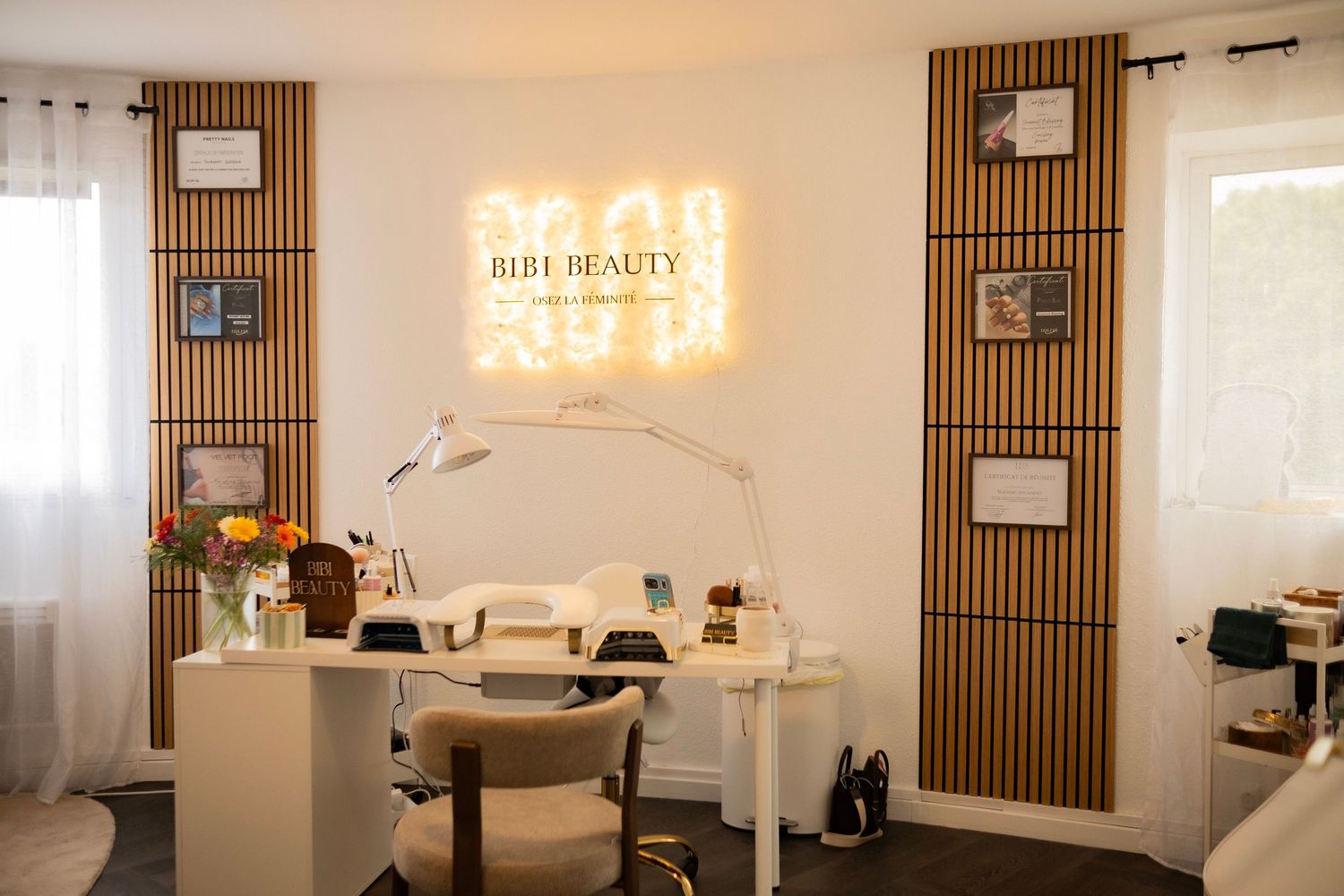 Bibi Beauty salon interior with illuminated logo sign, white desk, and decorative wood slat wall panels.