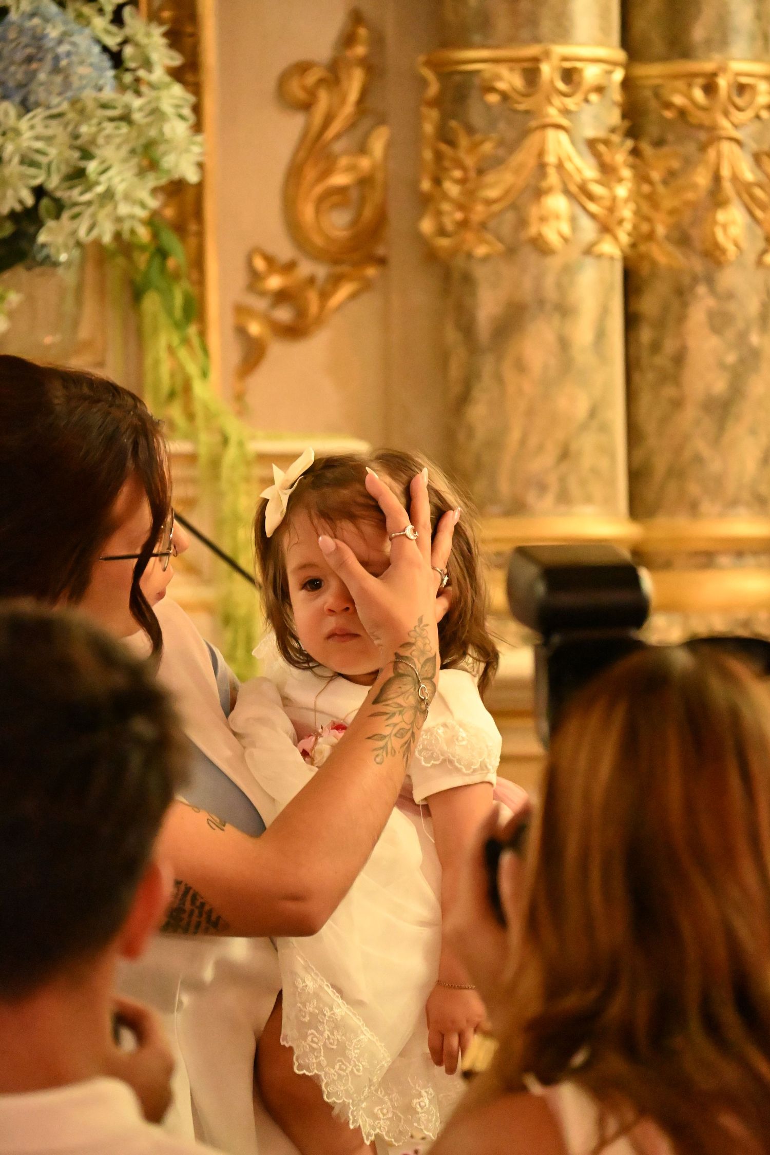A couple shares a joyful moment during their first dance at a wedding reception with ornate golden decor.