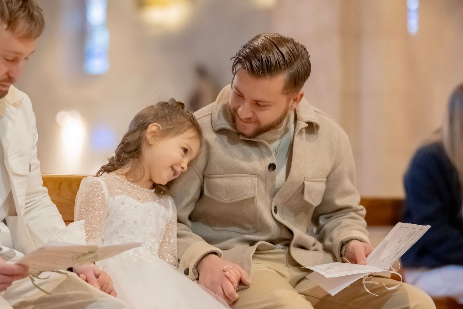 A family sits together at a table writing and drawing with paper and pens in a warmly lit room.