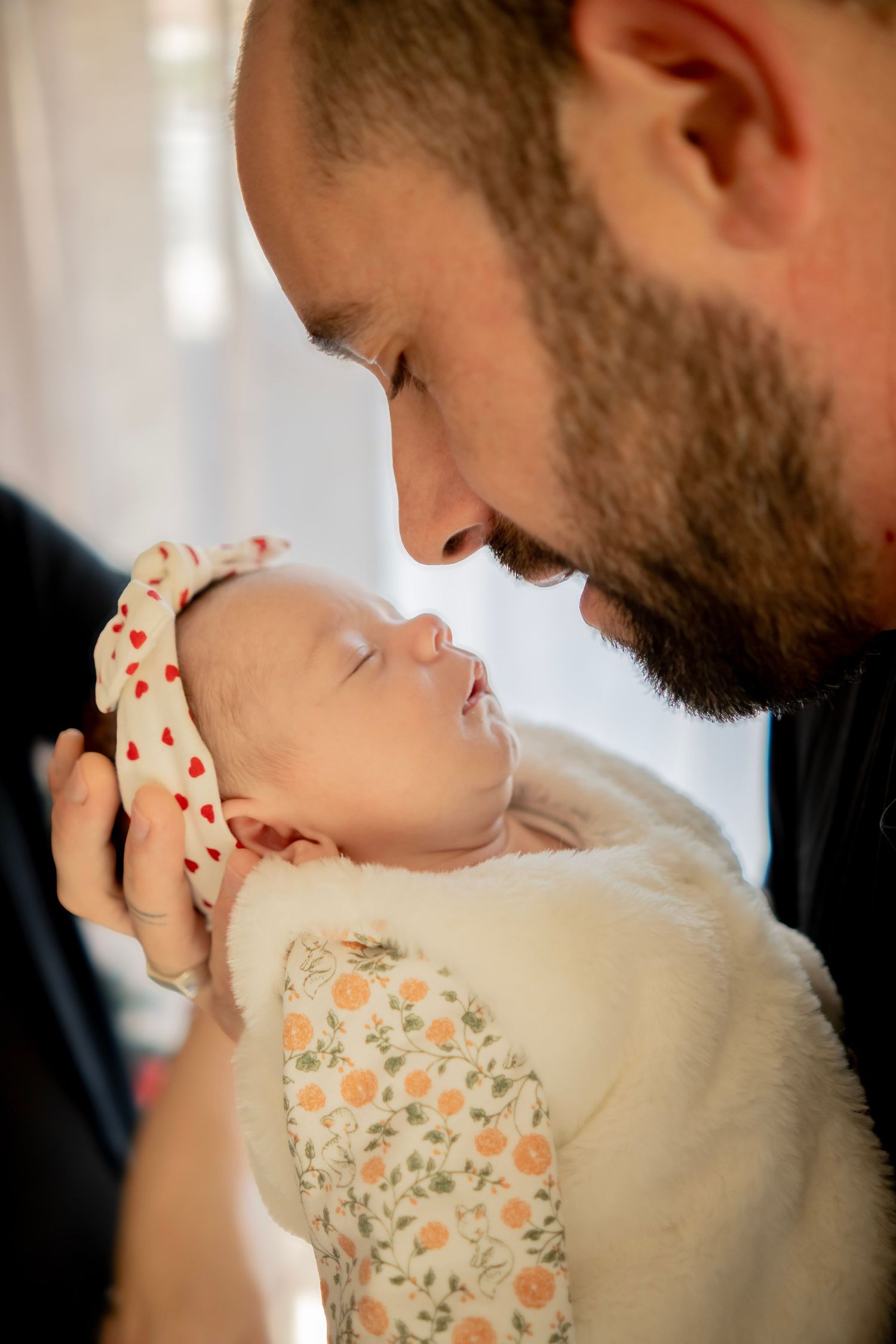 A tender moment between a parent and baby wearing a floral outfit while being held close.