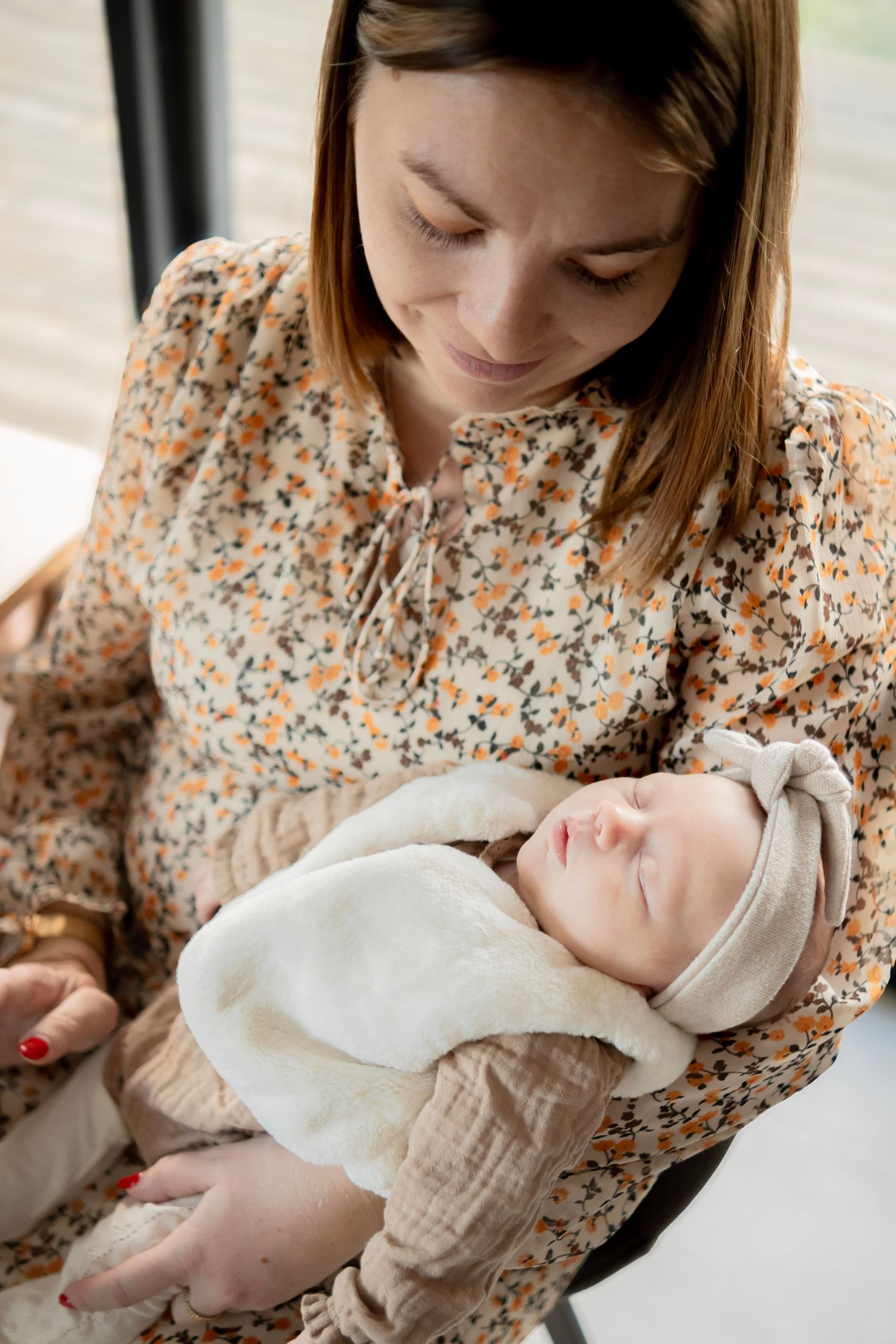 A tender moment captured in a series of photos showing a parent in a floral blouse cradling a newborn baby in white.