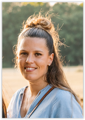 Woman with hair in messy bun backlit by golden sunset light.