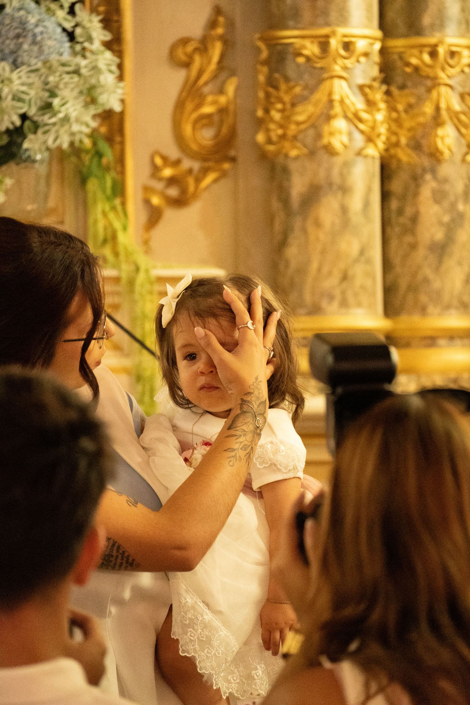 A couple shares an emotional moment during their wedding ceremony in an ornate gold-decorated church.
