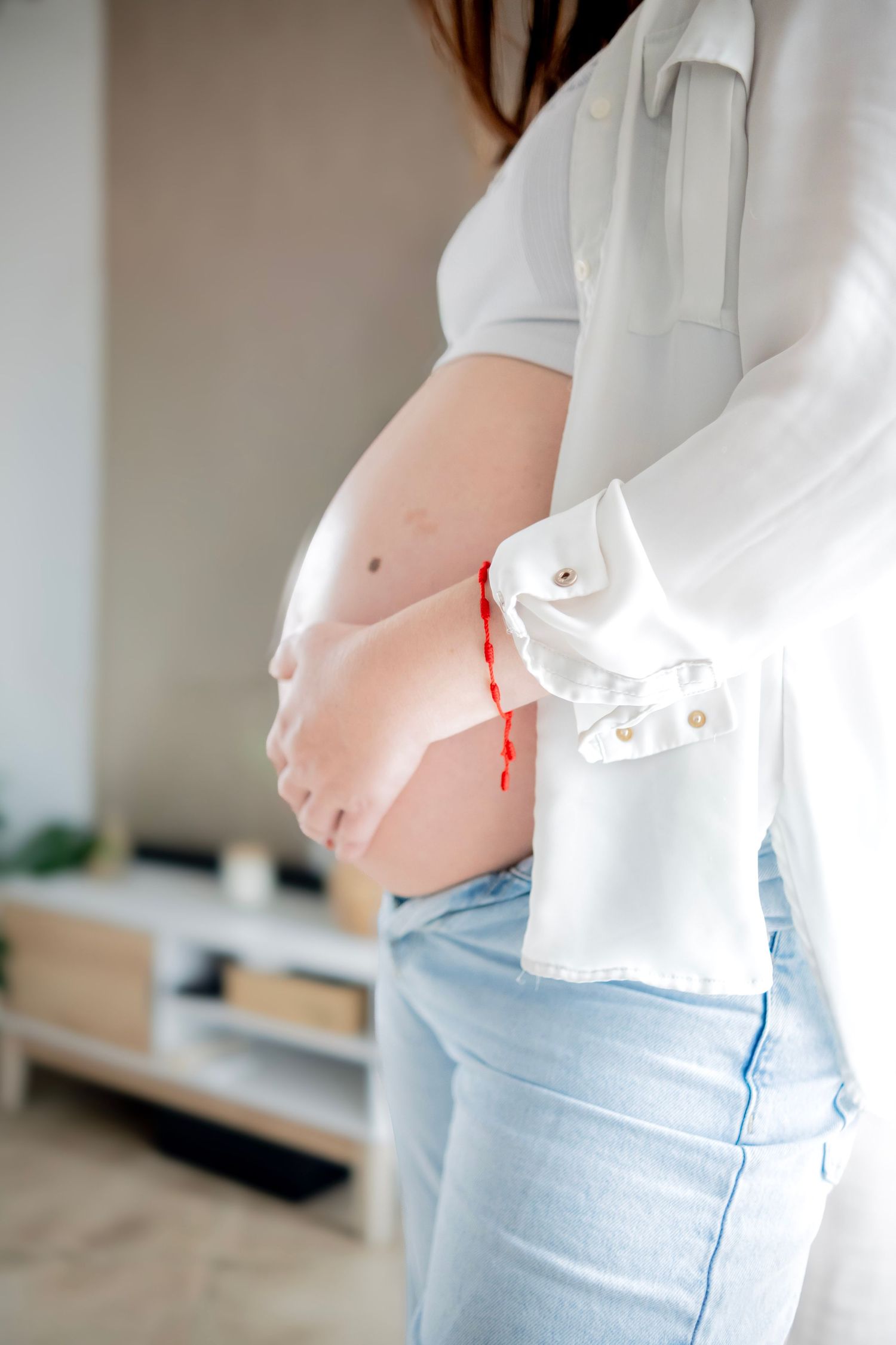 Side view of a pregnant woman's growing belly shown in a series of progressive photos wearing light jeans and white top.
