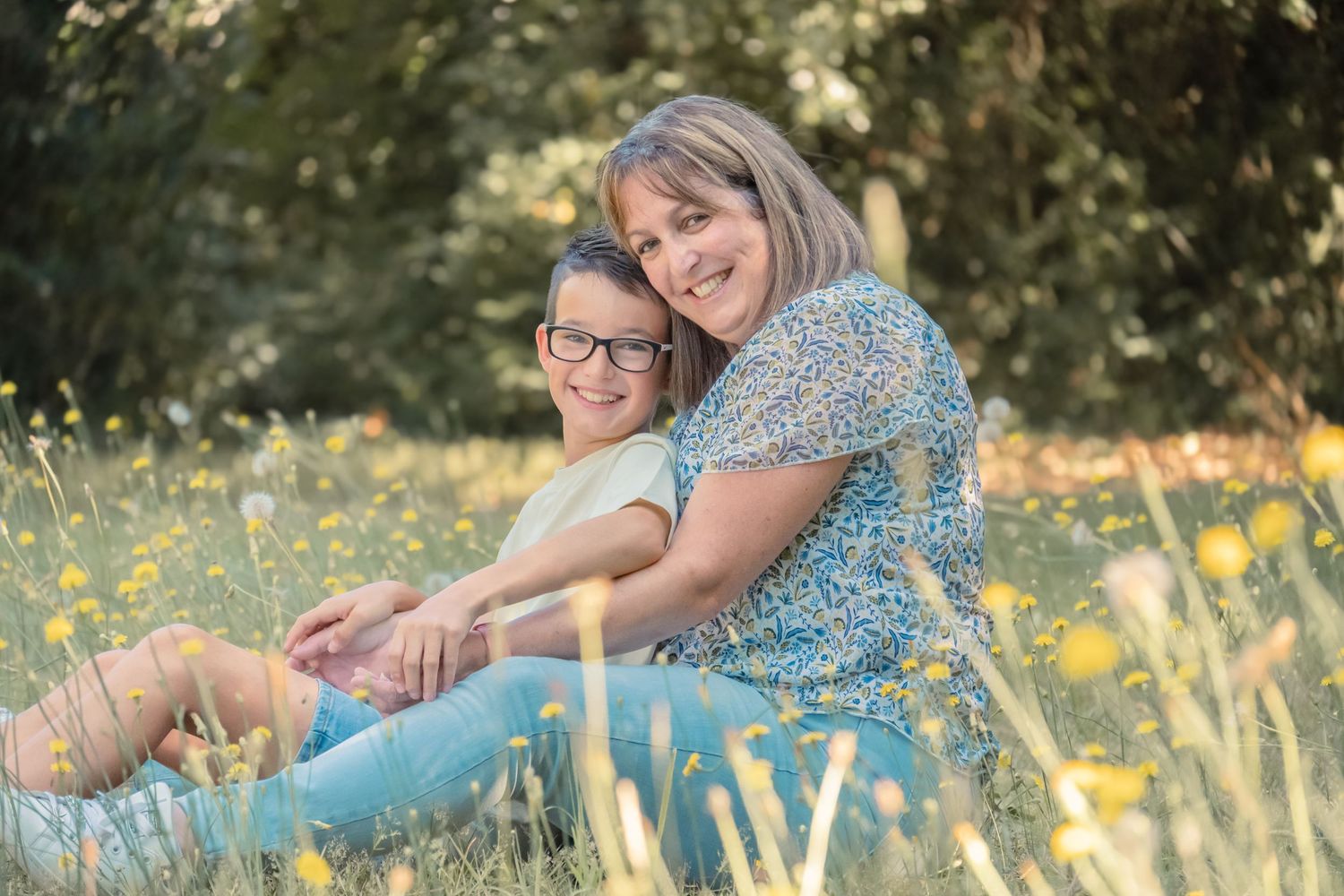 A couple sits in a blooming wildflower meadow during a sunny summer photo session.
