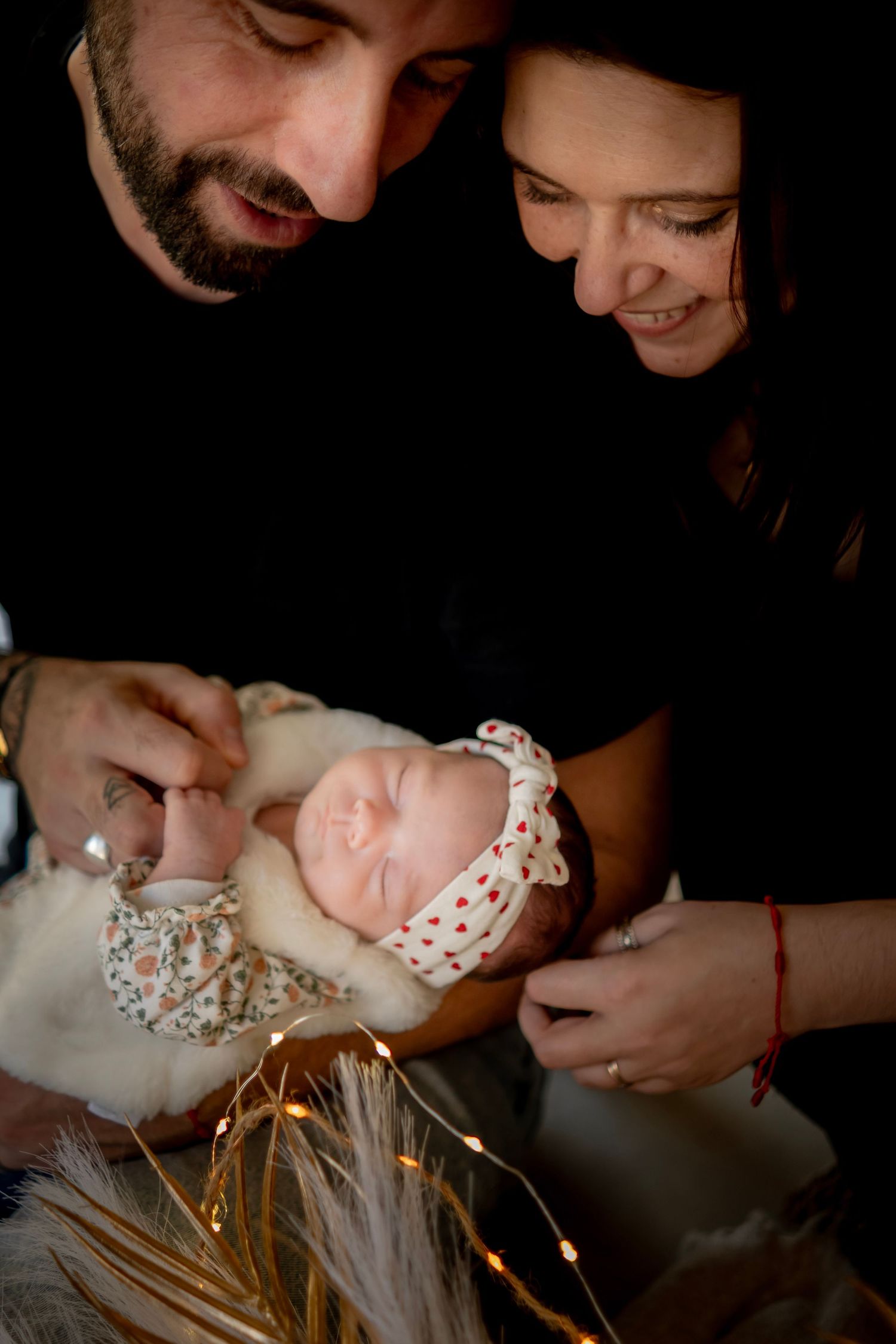 A tender moment captured in black and white as people gaze lovingly at a sleeping newborn baby.