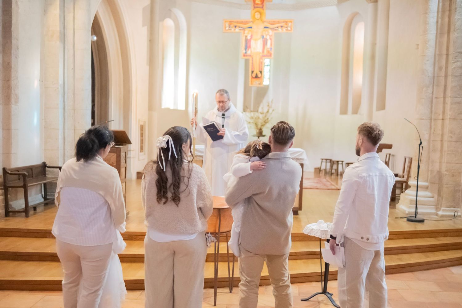 A line of people in white robes stand in a church sanctuary during a religious ceremony.