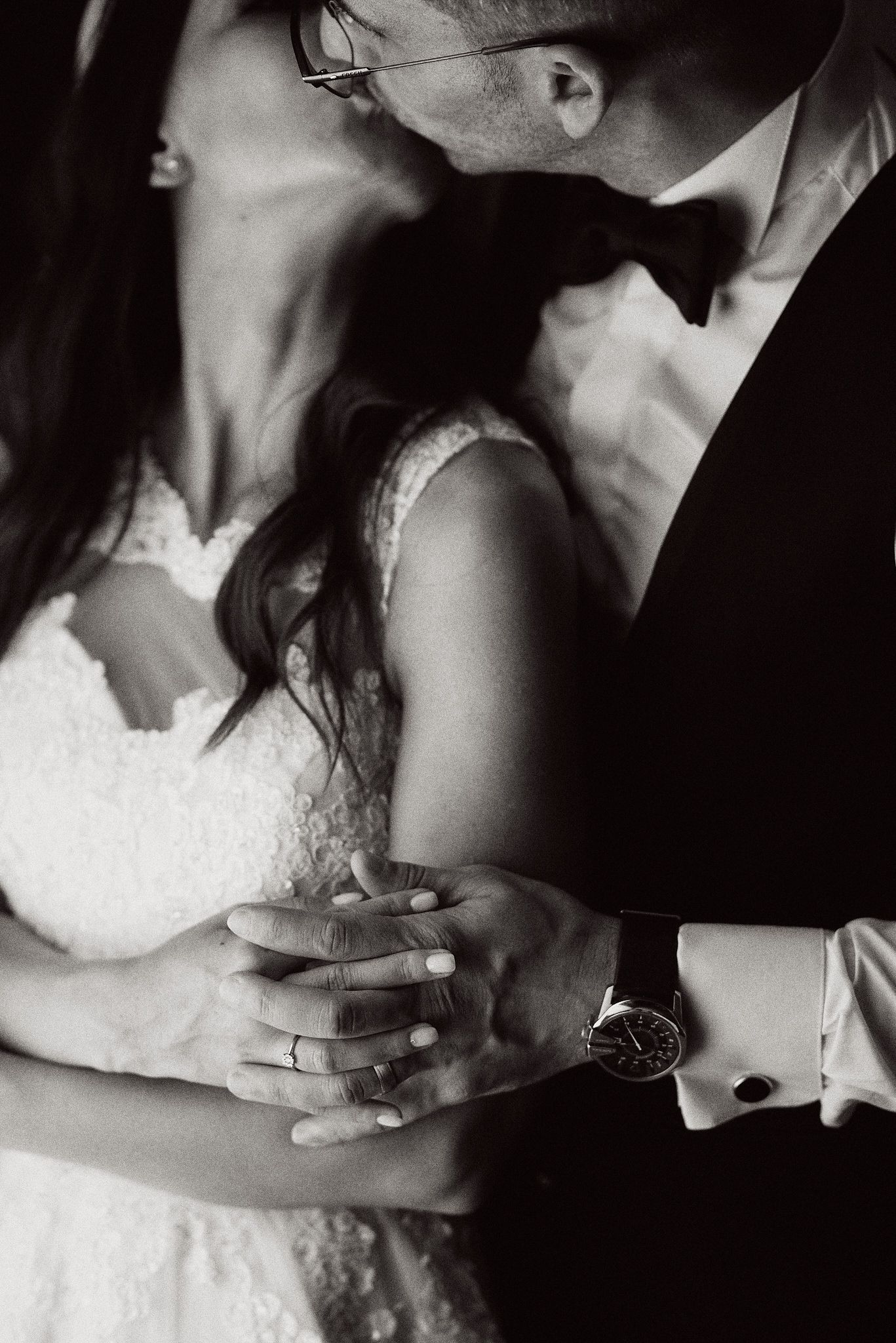 Intimate black and white photo of couple in wedding attire sharing close embrace.
