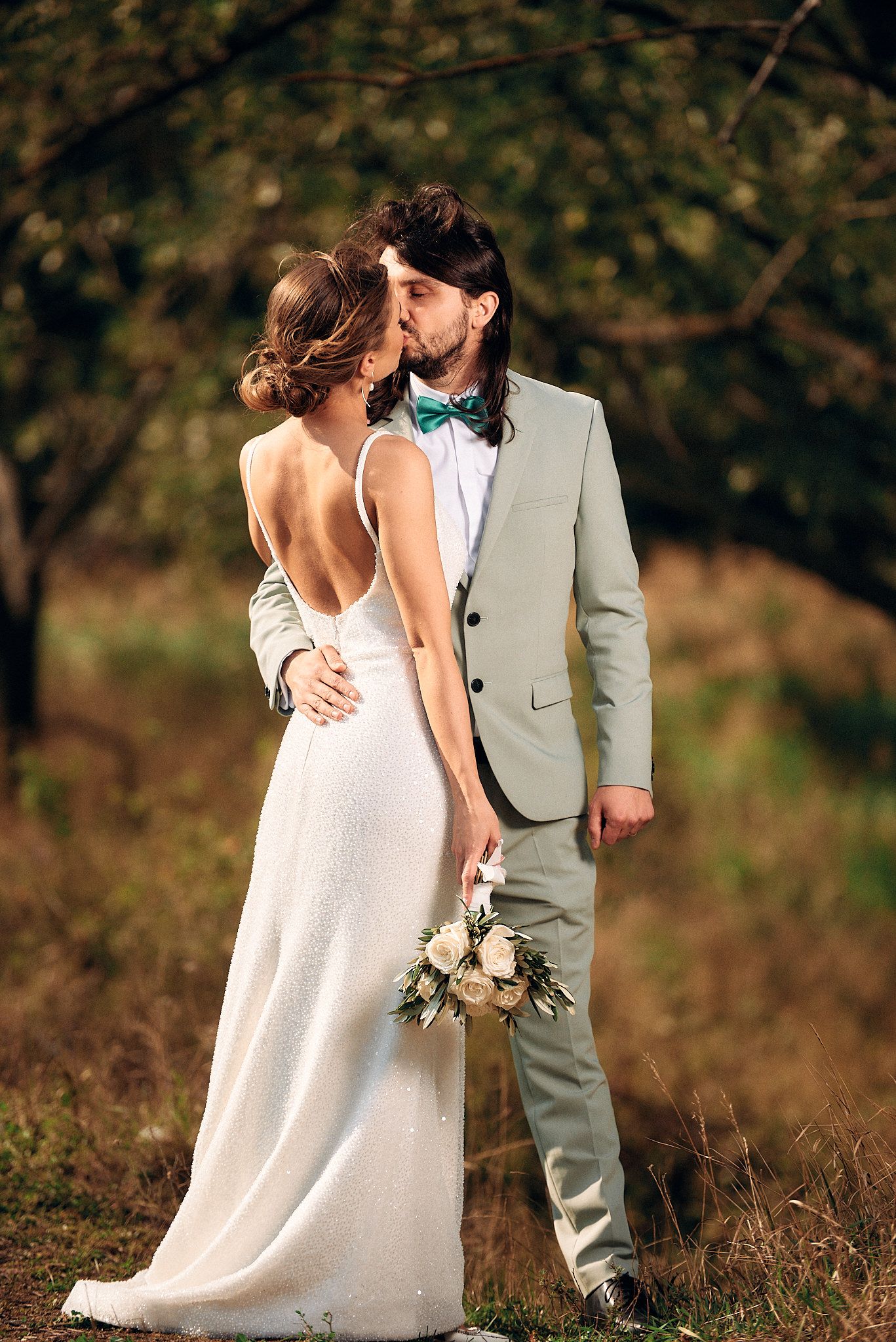 Romantic wedding portrait of couple embracing in natural outdoor setting.
