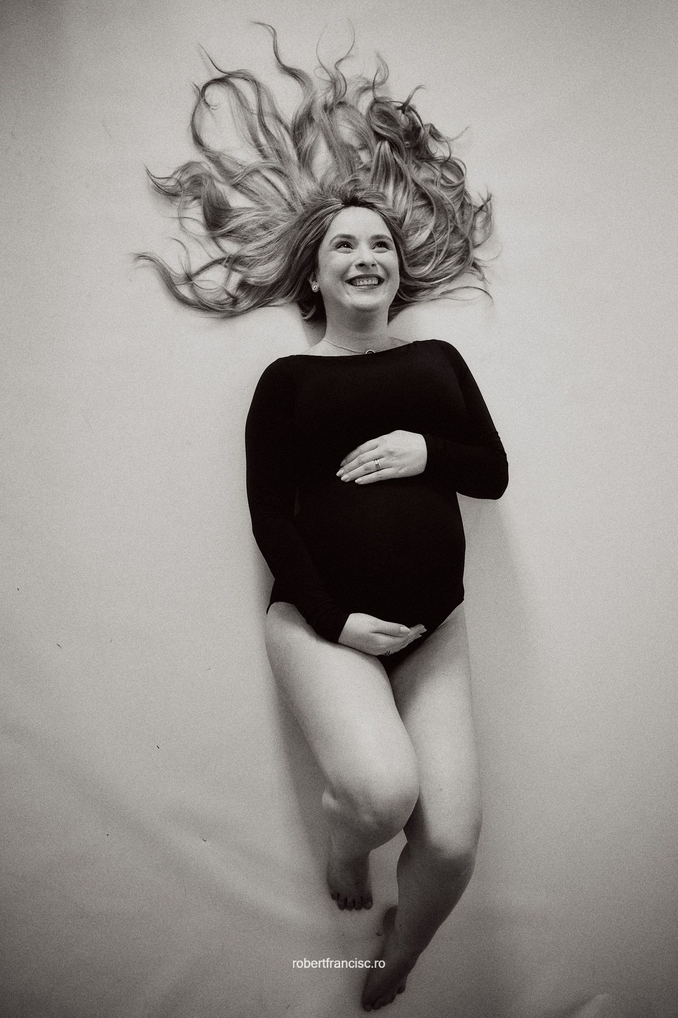 Artistic black and white portrait of a person wearing a black leotard with flowing hair against a light background.