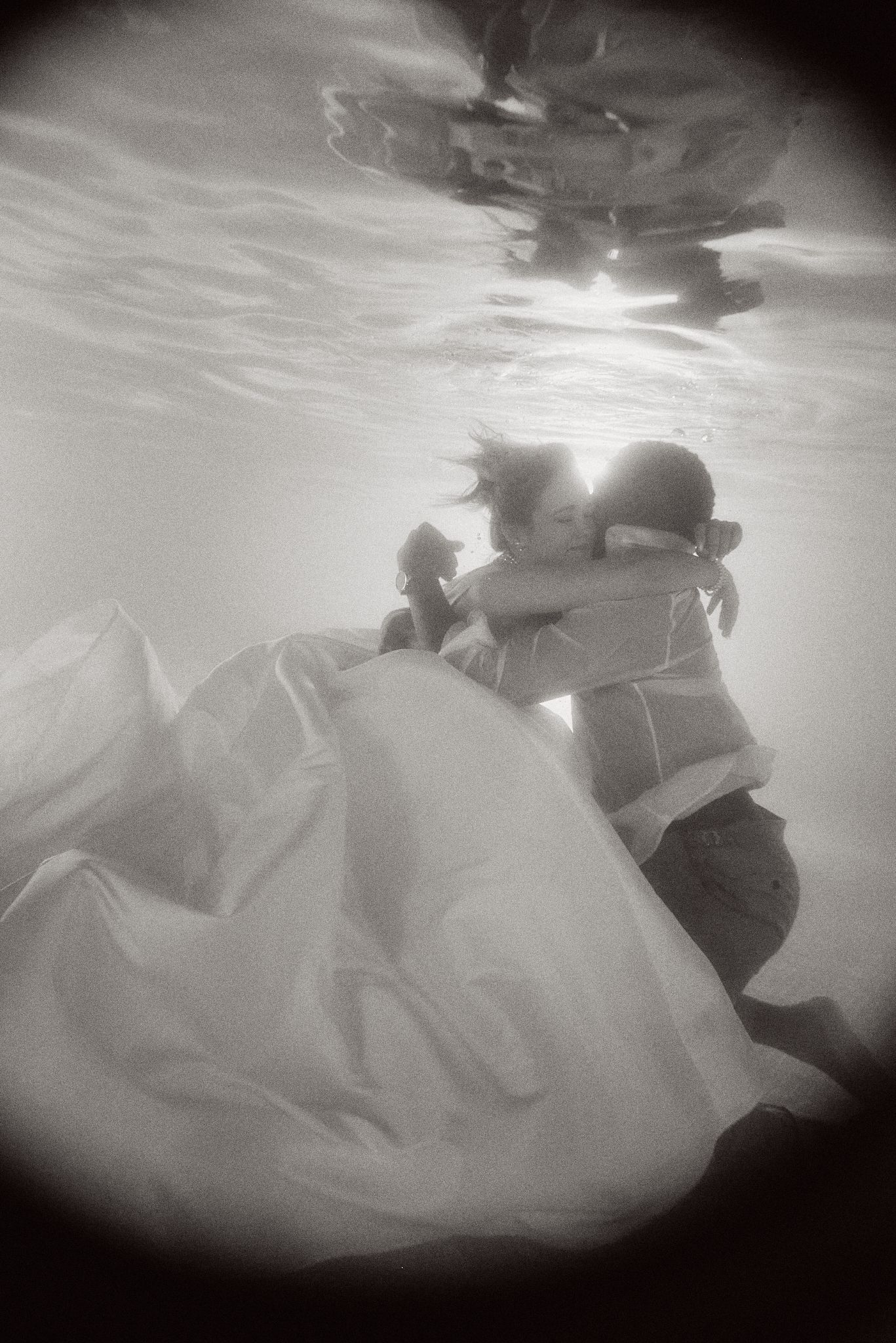 Underwater wedding photography captures a dreamy moment with flowing white dress.