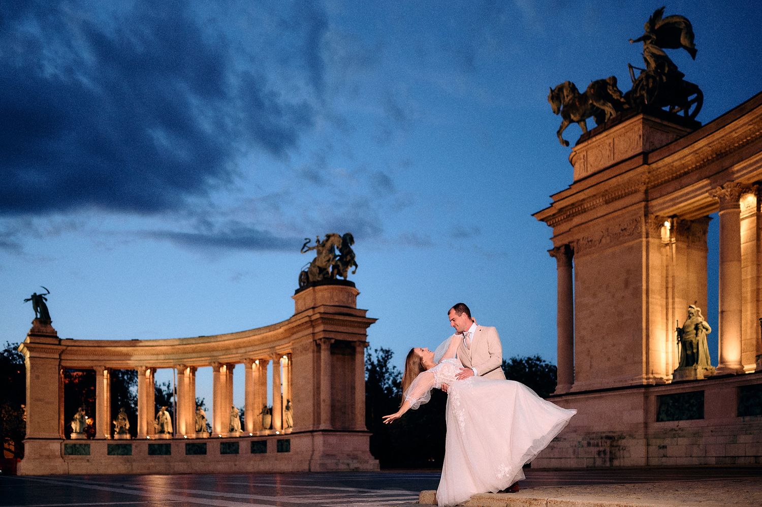 A dramatic wedding photo at Heroes Square monument in Budapest during blue hour.