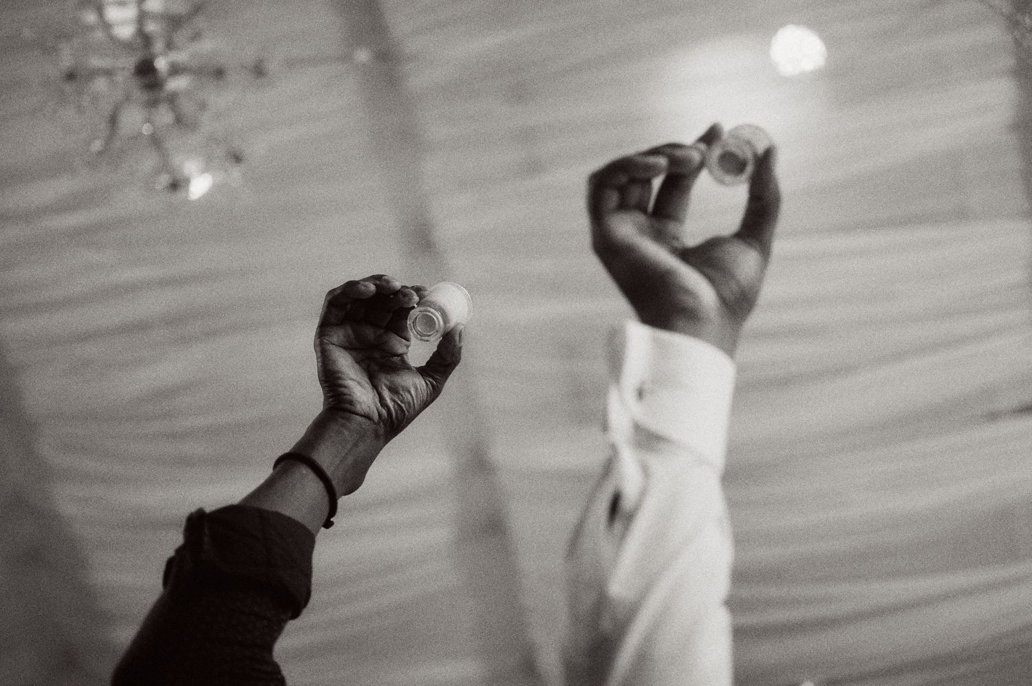 Black and white silhouette of hands raised in celebration during wedding dance.