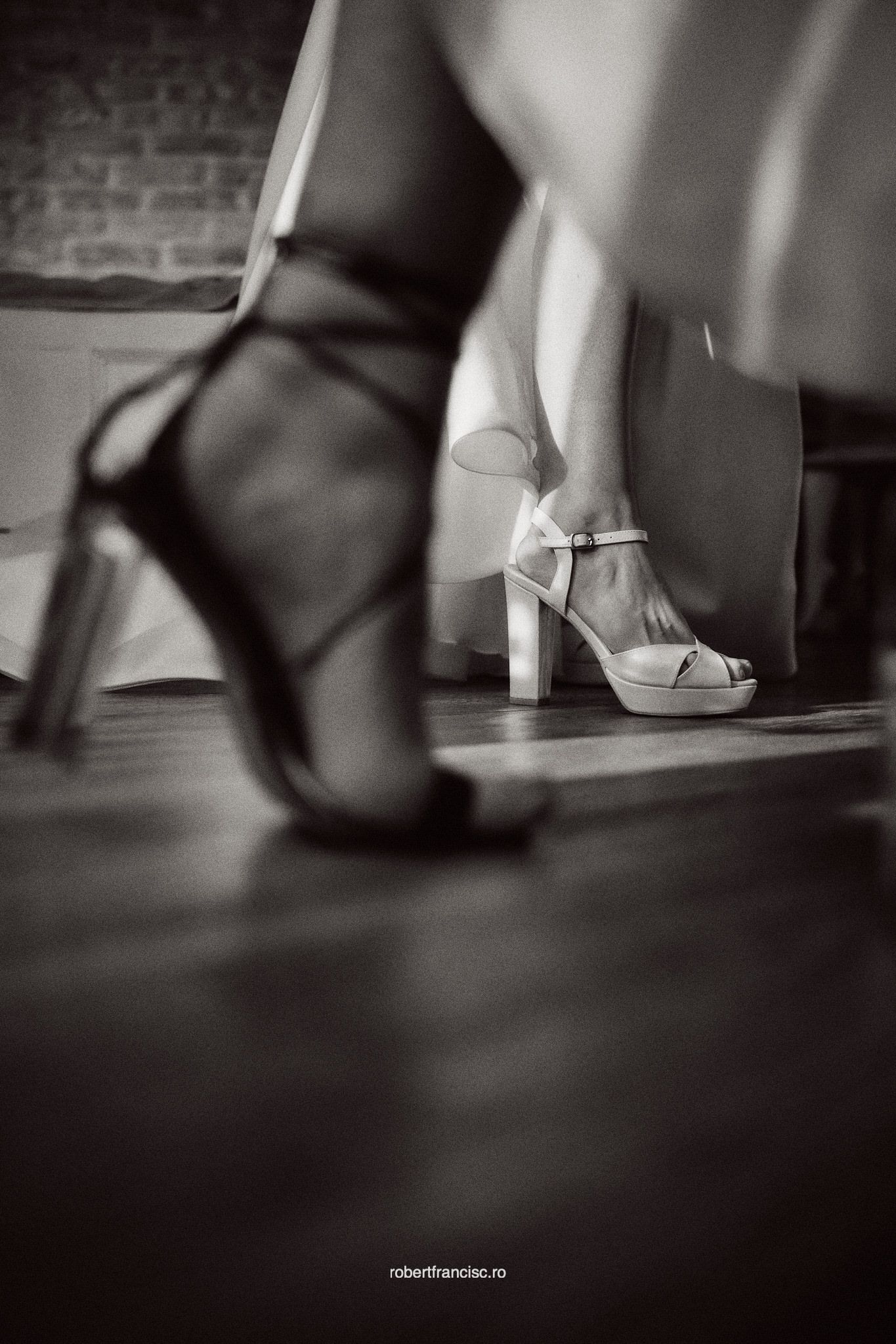 Black and white artistic series of elegant high heels dancing across a hardwood floor in dramatic lighting.