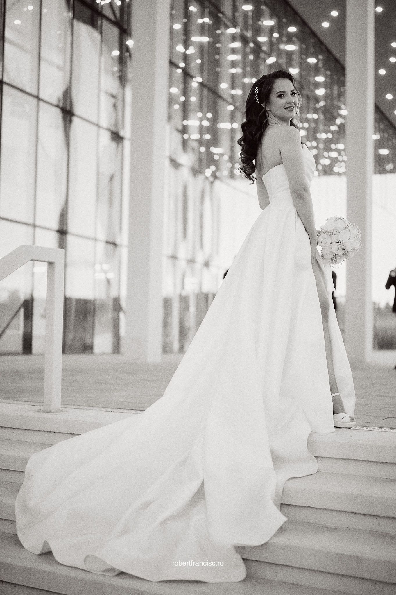 A series of black and white bridal portraits showing a flowing white wedding gown against a modern architectural backdrop.